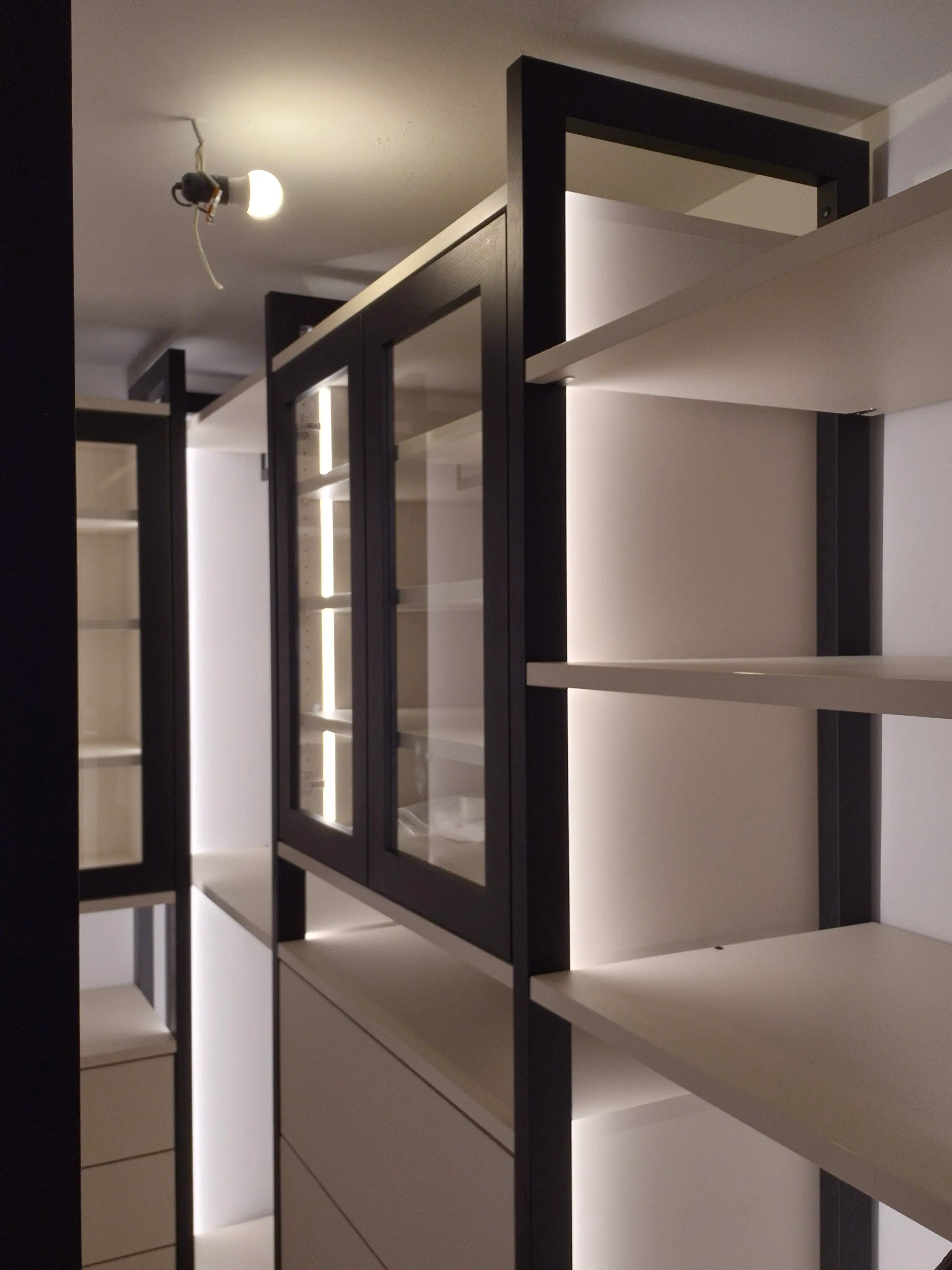 Maßgefertigtes Ankleidezimmer mit LED-Beleuchtung, Glasvitrine und offenem Regalsystem im Boutique-Stil