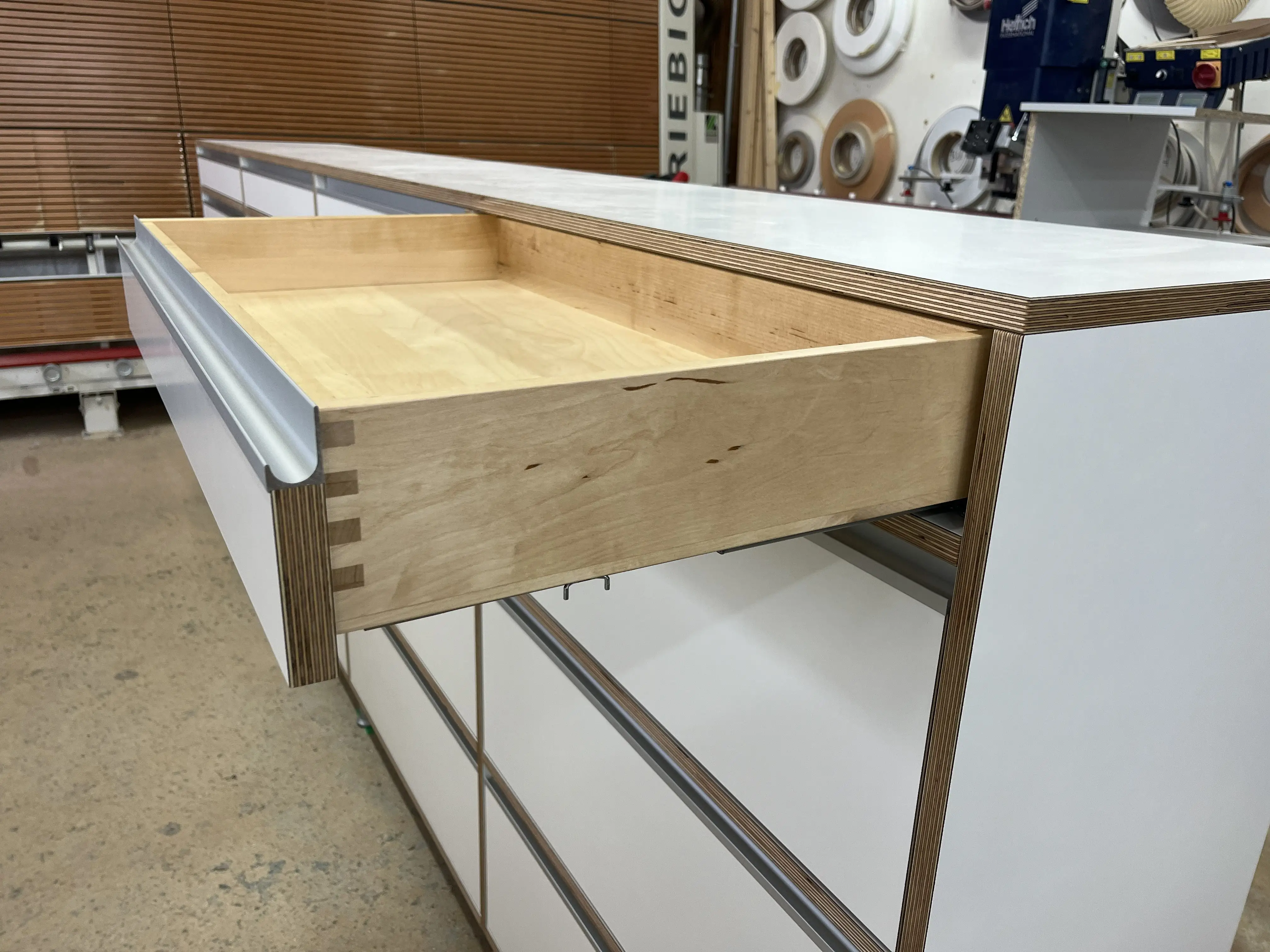 Massiver fingergezinkter Schubkasten aus Birke an einem maßgefertigten Multiplex-Sideboard mit weißen HPL-Fronten in Viernheim