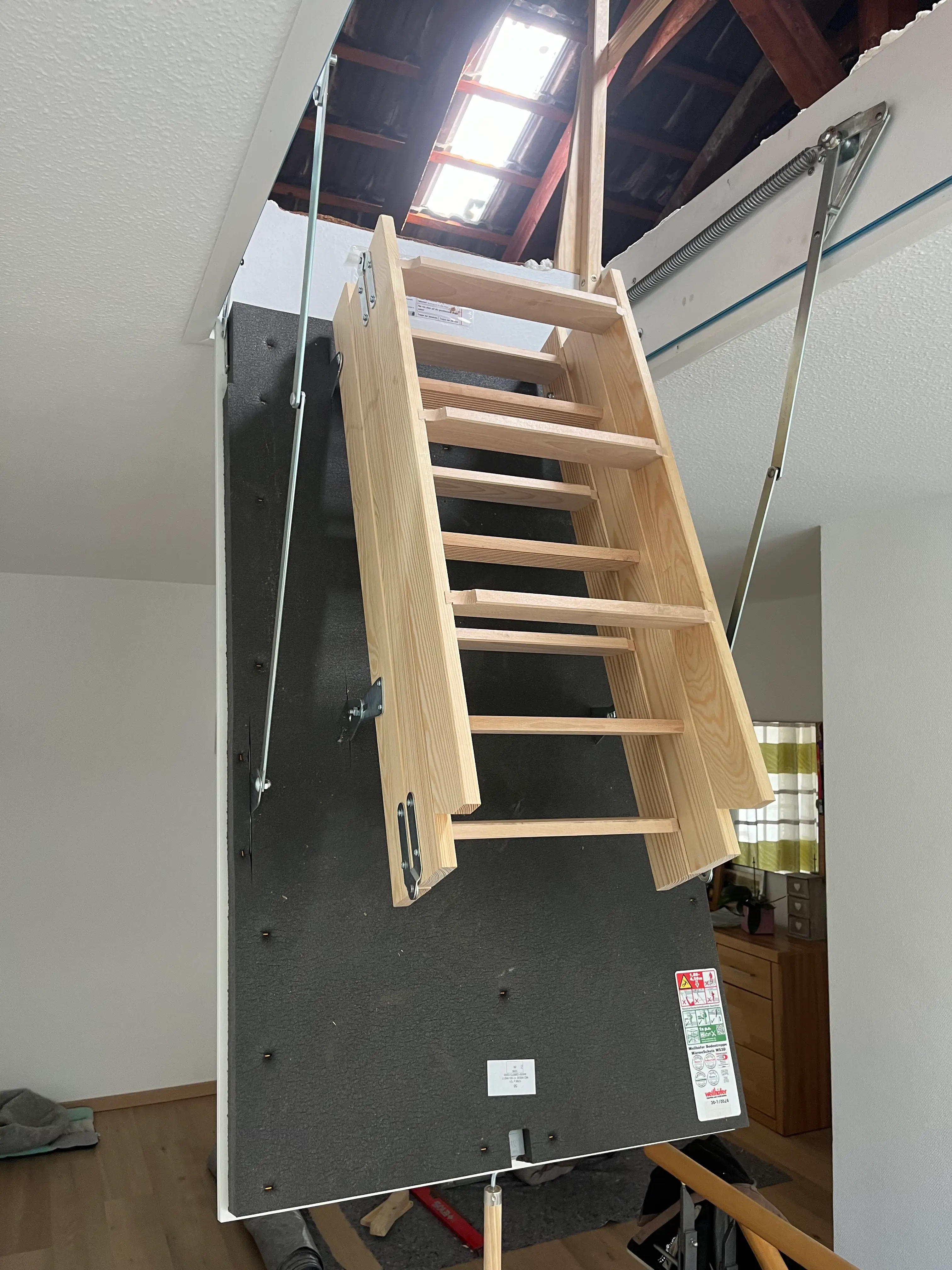 Geöffnete Wellhöfer Dachlukentreppe mit wärmegedämmtem Deckenelement und Holzleiter in Weinheim.
