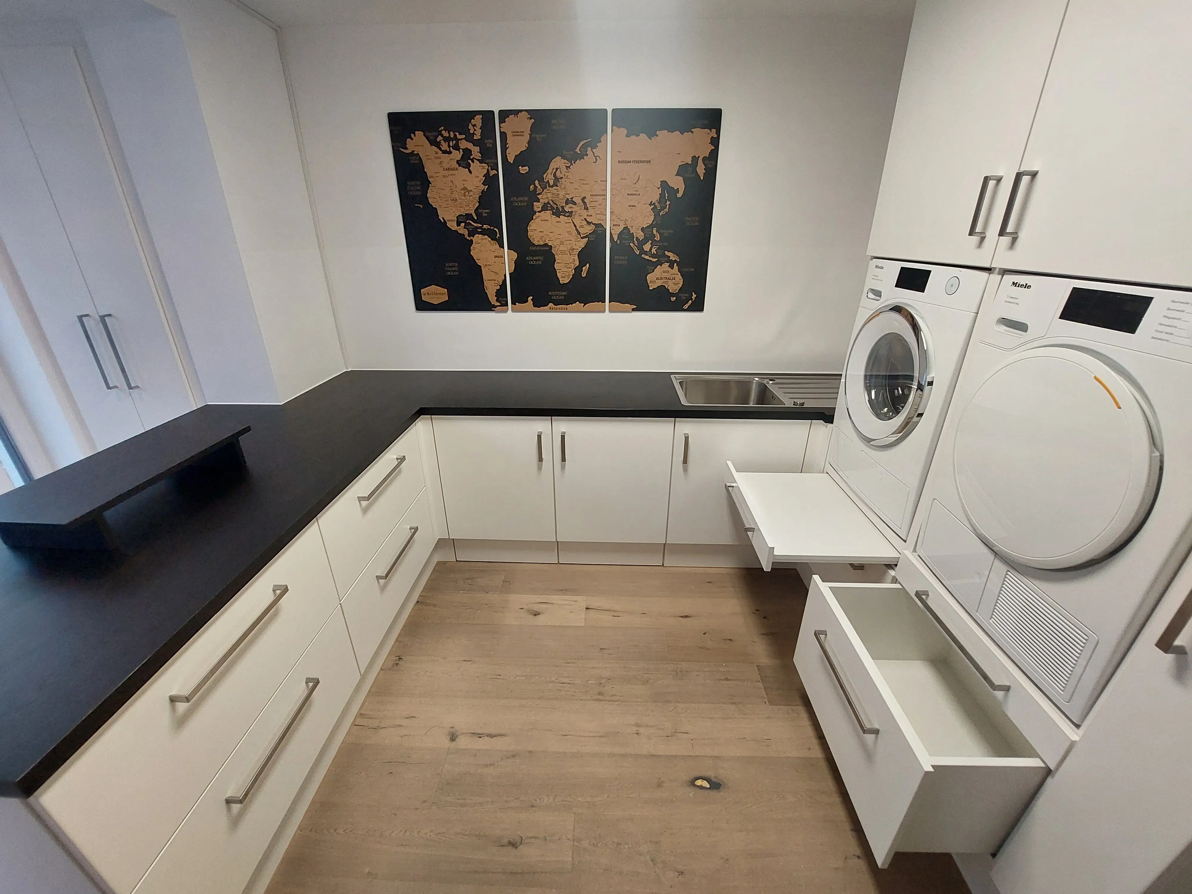 Moderner maßgefertigter Hauswirtschaftsraum mit Waschmaschinenhochschrank, viel Stauraum, schwarzen HPL-Arbeitsplatten und integriertem Tablarboard in Walldorf.