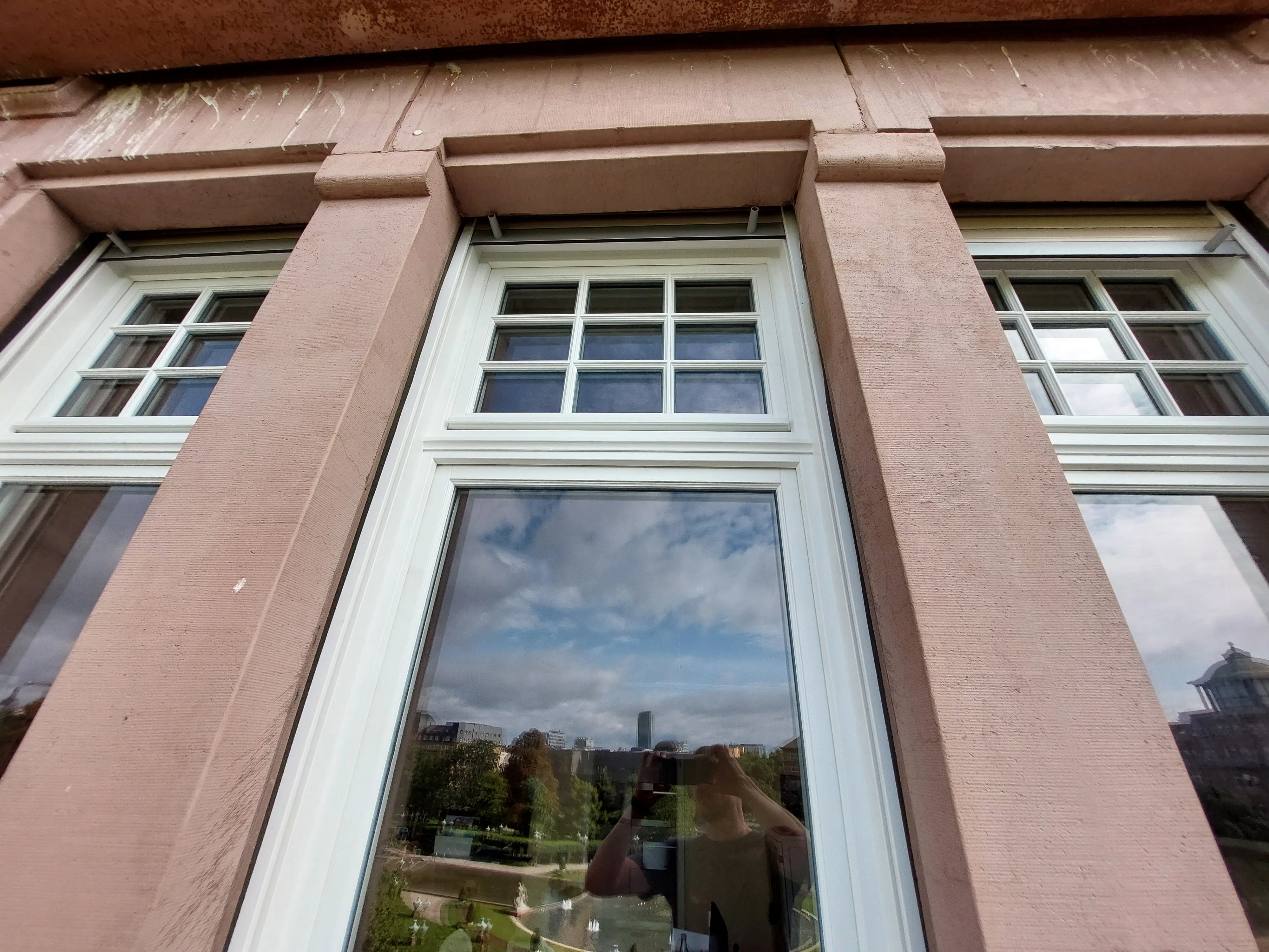 Außenansicht der neuen denkmalgerechten Holzfenster mit Sprossen in historischer Sandsteinfassade am Friedrichsplatz in Mannheim.