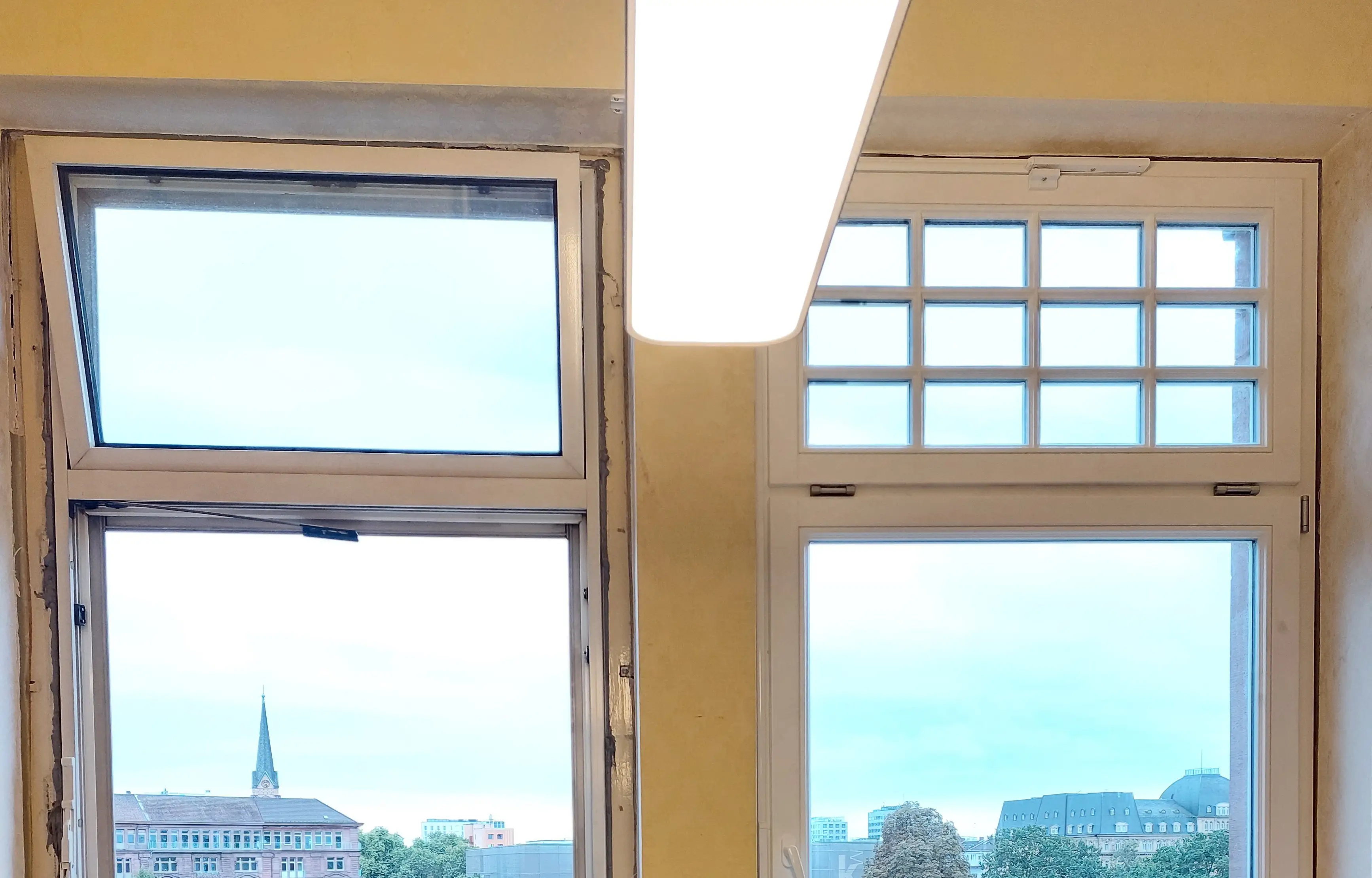 Vorher-Nachher-Vergleich eines alten Aluminiumfensters und eines neuen denkmalgerechten Holzfensters mit Sprossen am Friedrichsplatz in Mannheim.