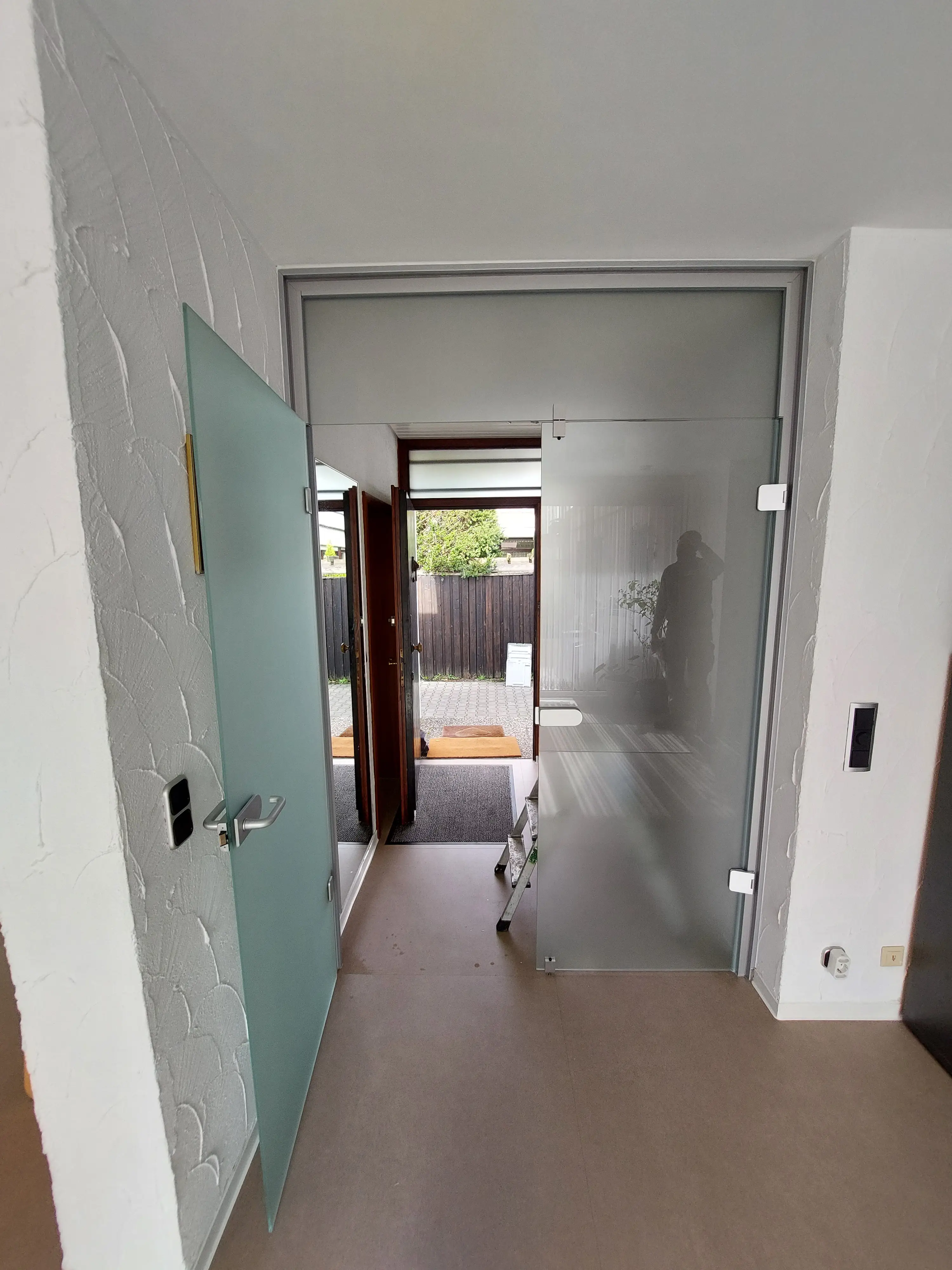 Geöffnete satinierte Glastüranlage mit Oberlicht im modernen Eingangsbereich eines Wohnhauses in Viernheim