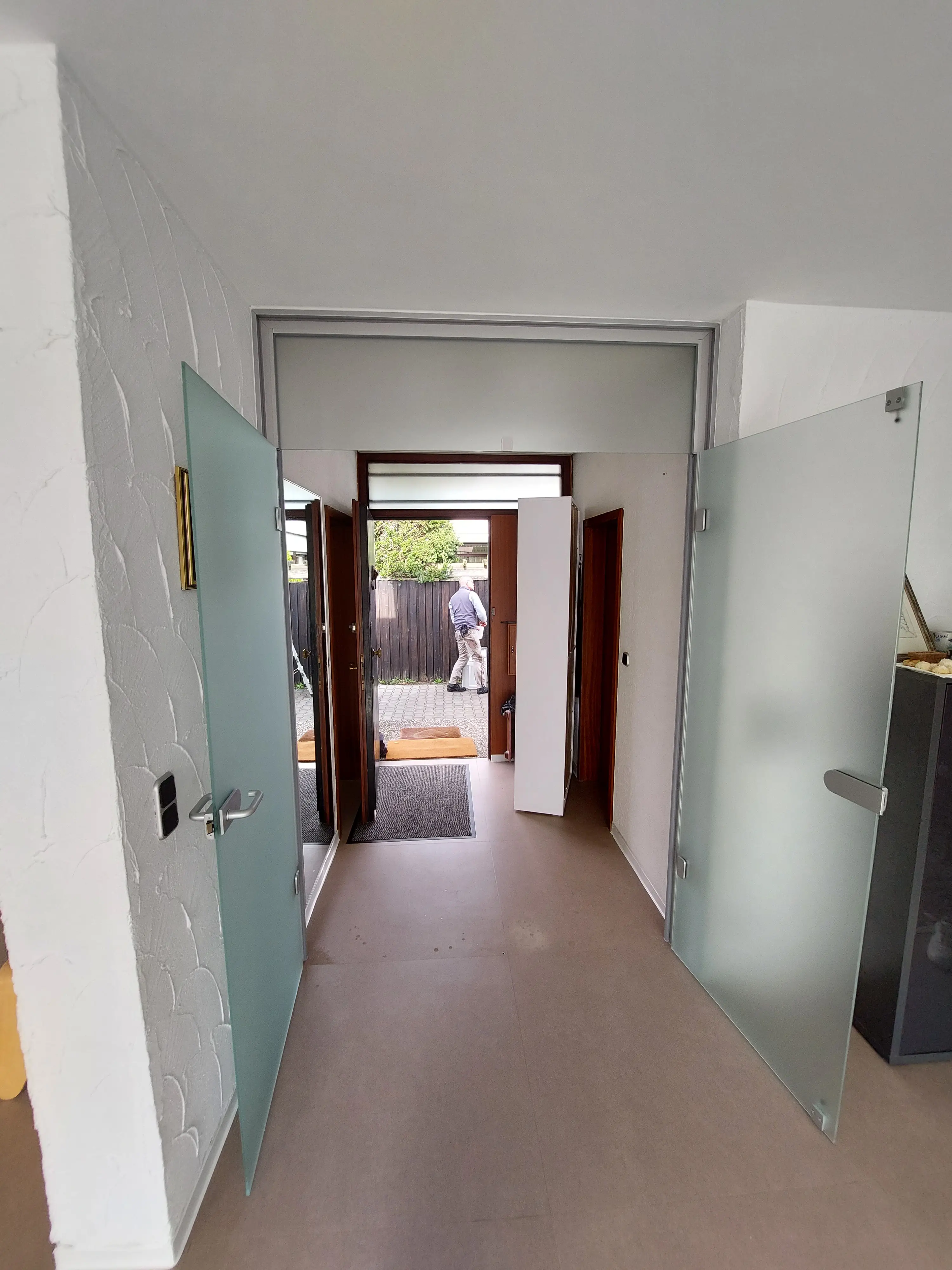 Geöffnete satinierte Ganzglas-Türanlage mit Oberlicht im modernen Eingangsbereich eines Wohnhauses in Viernheim