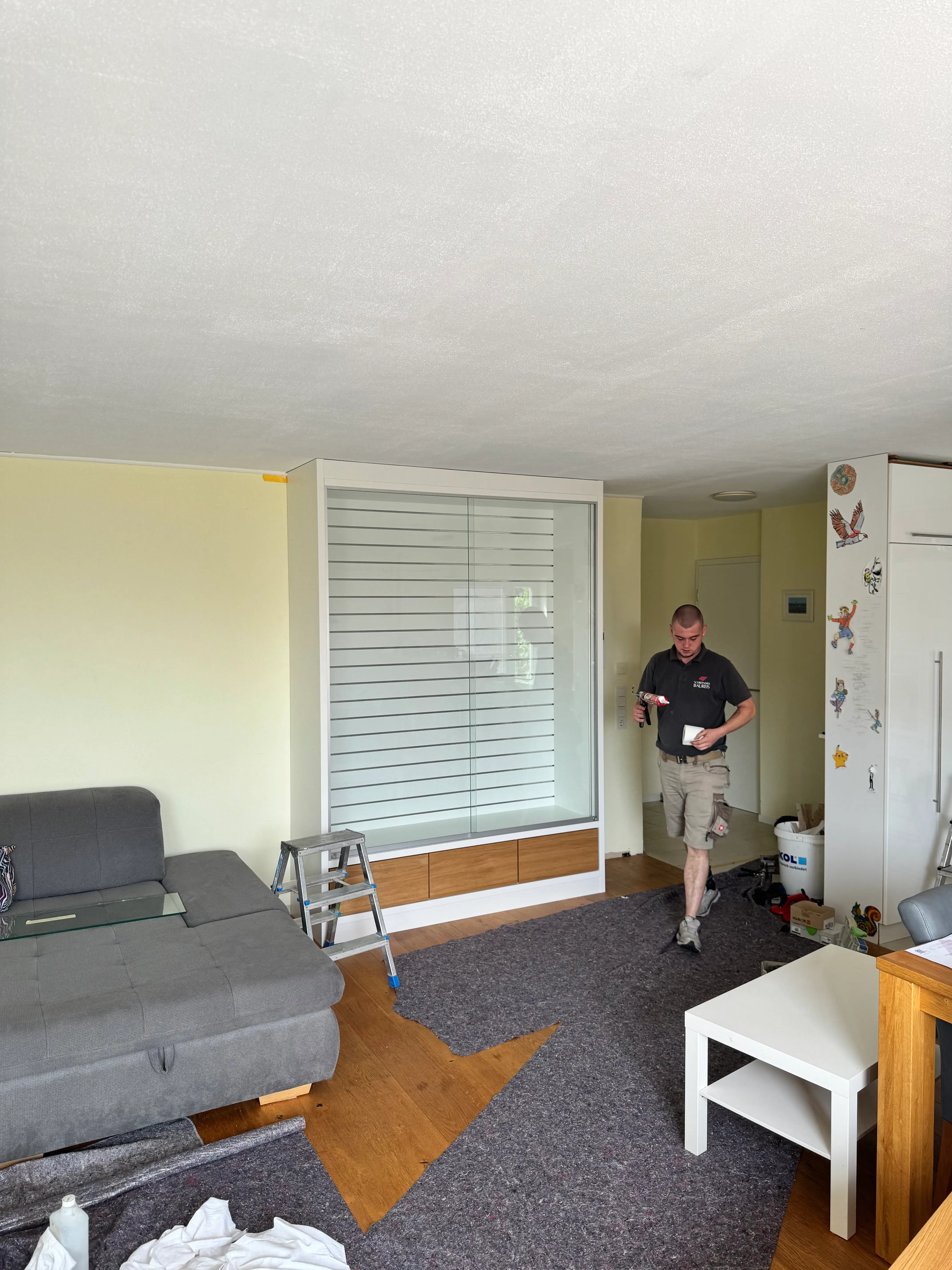 Individuell gefertigtes Präsentationsmöbel mit Glasfront, Beleuchtung und Eiche-Elementen während der Montage im Wohnraum in Lampertheim.