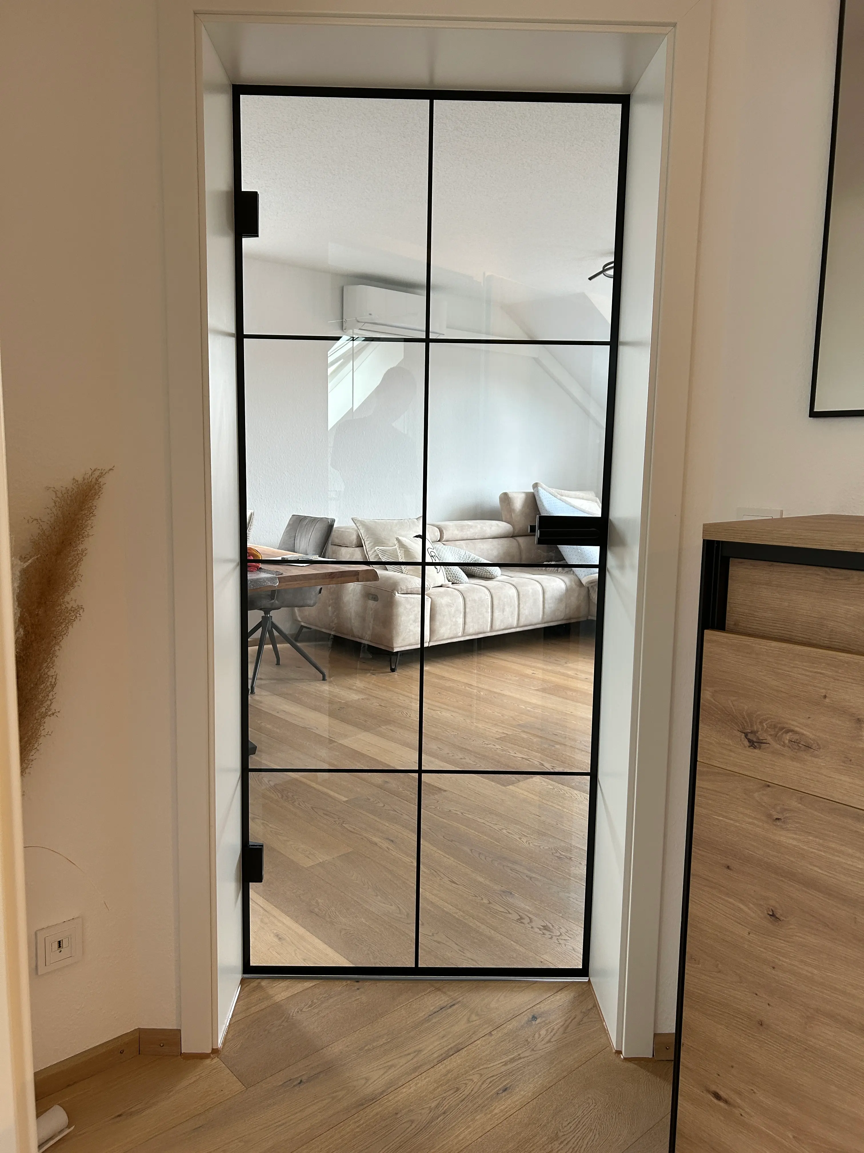Transparente Loft-Glastür mit schwarzem Sprossendesign und Blick in den Wohnbereich in Heddesheim