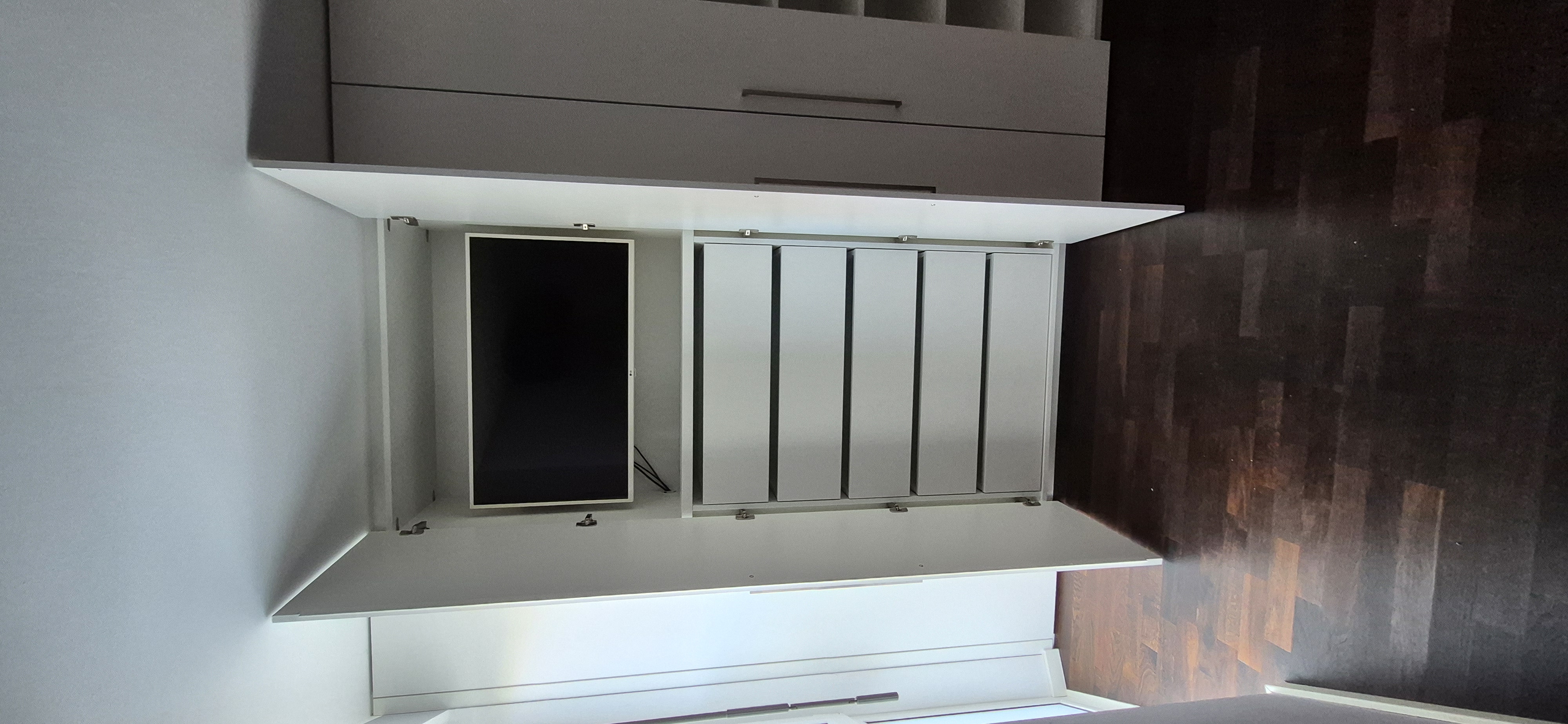 Geöffneter maßgefertigter Einbauschrank mit integriertem TV-Fach, großzügigen Schubladen und verdeckter Medienlösung. Individuell geplanter Schrankeinbau nach Maß für Wohn- oder Schlafzimmer in Weinheim.