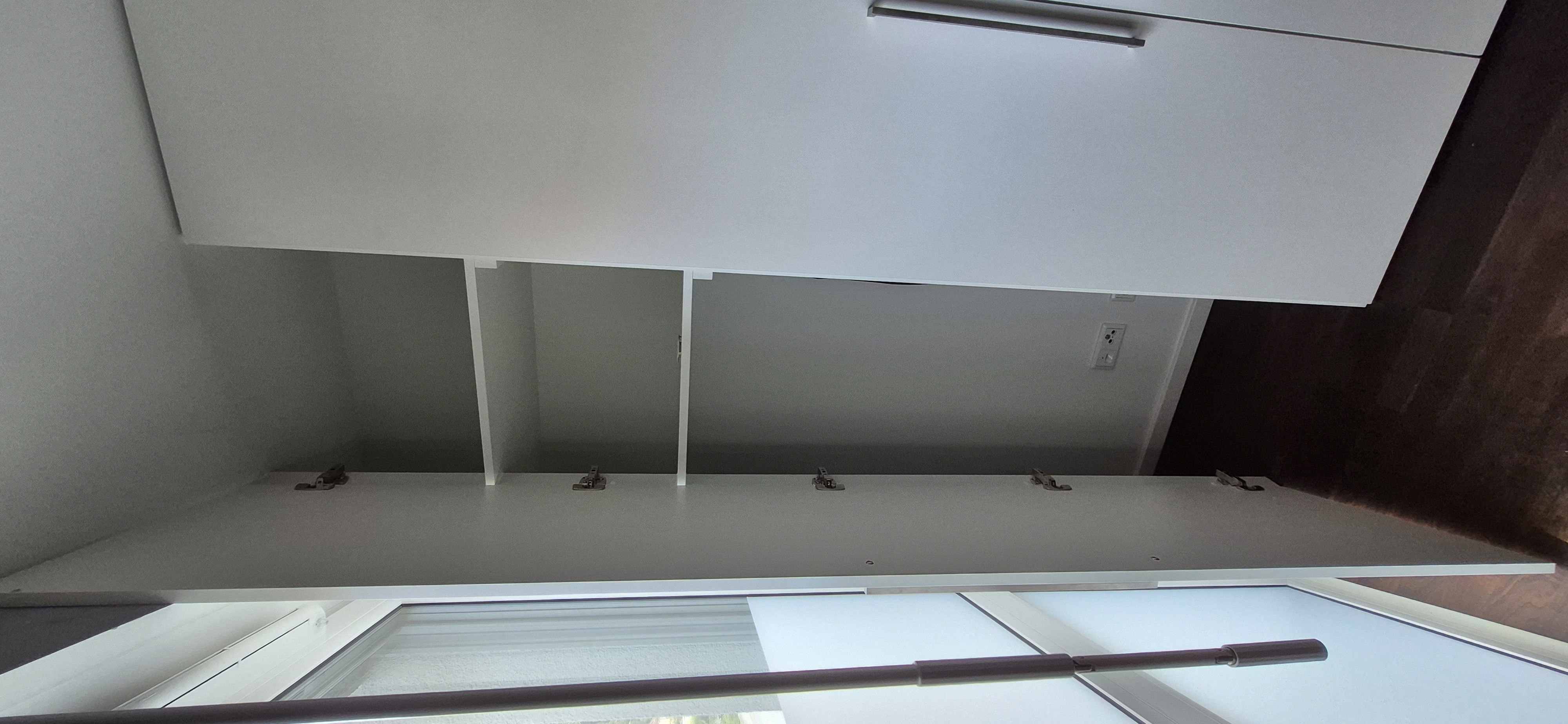 Geöffneter maßgefertigter Blendrahmenschrank im Eckbereich einer Einbauschrankanlage. Die Sonderlösung nutzt den Raum bis in die Ecke optimal aus und schafft zusätzlichen, leicht zugänglichen Stauraum.