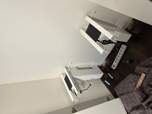 Vorbereitung eines elektrisch höhenverstellbaren Schreibtischs im integrierten Homeoffice einer maßgefertigten Einbauschrankanlage. Die Antriebseinheiten und Elektroanschlüsse sind vor der Montage der Arbeitsplatte im Schrank installiert.