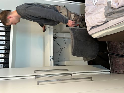 In die maßgefertigte Einbauschrankanlage integriertes Homeoffice mit elektrisch höhenverstellbarer Arbeitsplatte. Der Arbeitsplatz kann bei Bedarf genutzt und anschließend vollständig hinter den Schranktüren verborgen werden, sodass eine ruhige Schrankfron