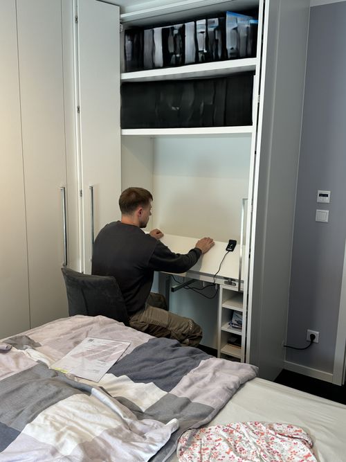 In den maßgefertigten Einbauschrank integriertes Homeoffice mit elektrisch höhenverstellbarer Arbeitsplatte. Der Arbeitsplatz lässt sich bei Bedarf nutzen und verschwindet anschließend wieder platzsparend hinter den Schranktüren.