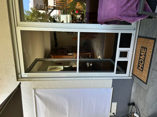 Geschlossene Neher Insektenschutz-Schiebetür mit Katzenklappe an einer Terrassentür in Ilvesheim.
