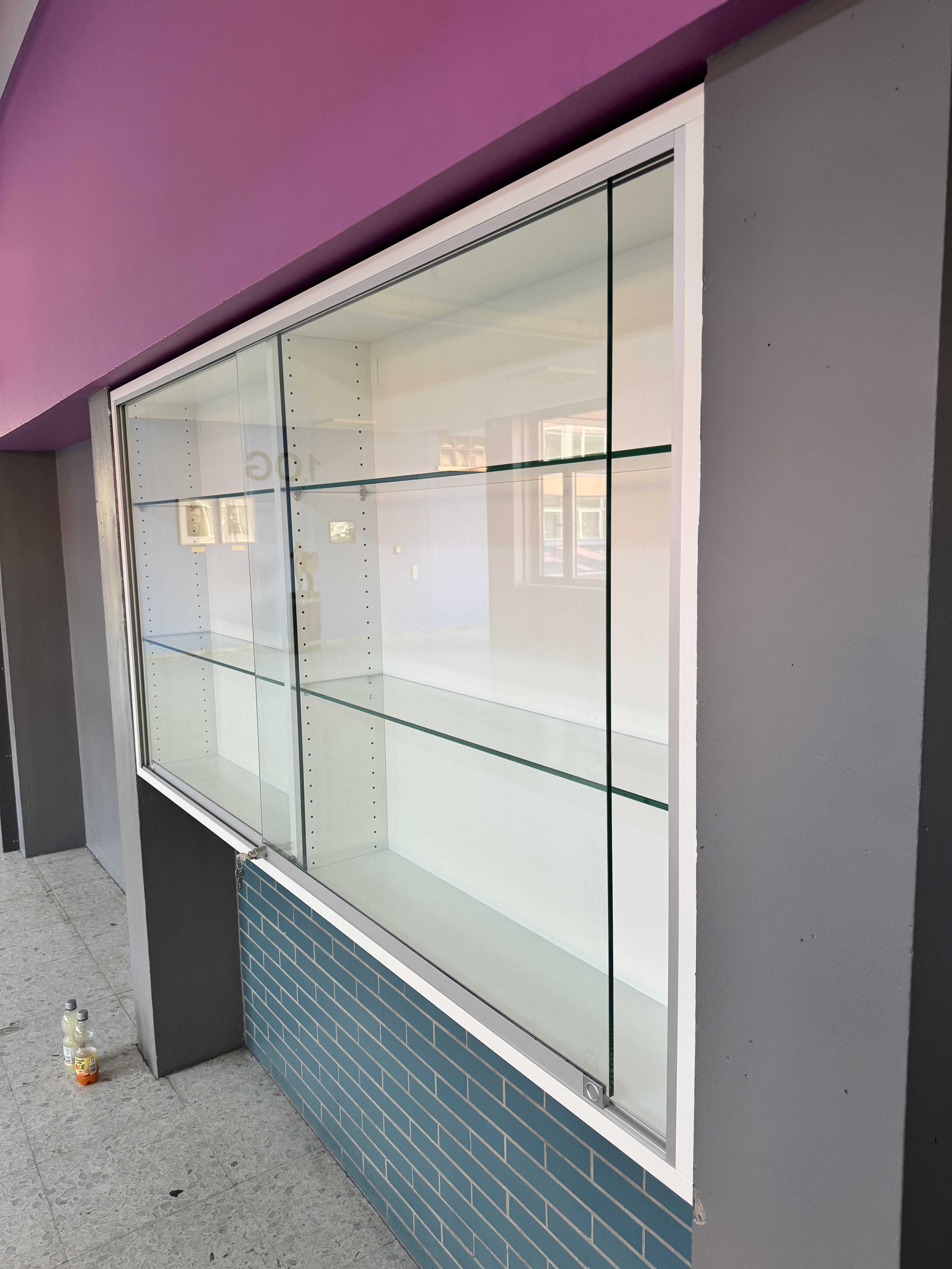 Seitenansicht einer maßgefertigten Glasvitrine mit ESG-Glasschiebetüren in Viernheim