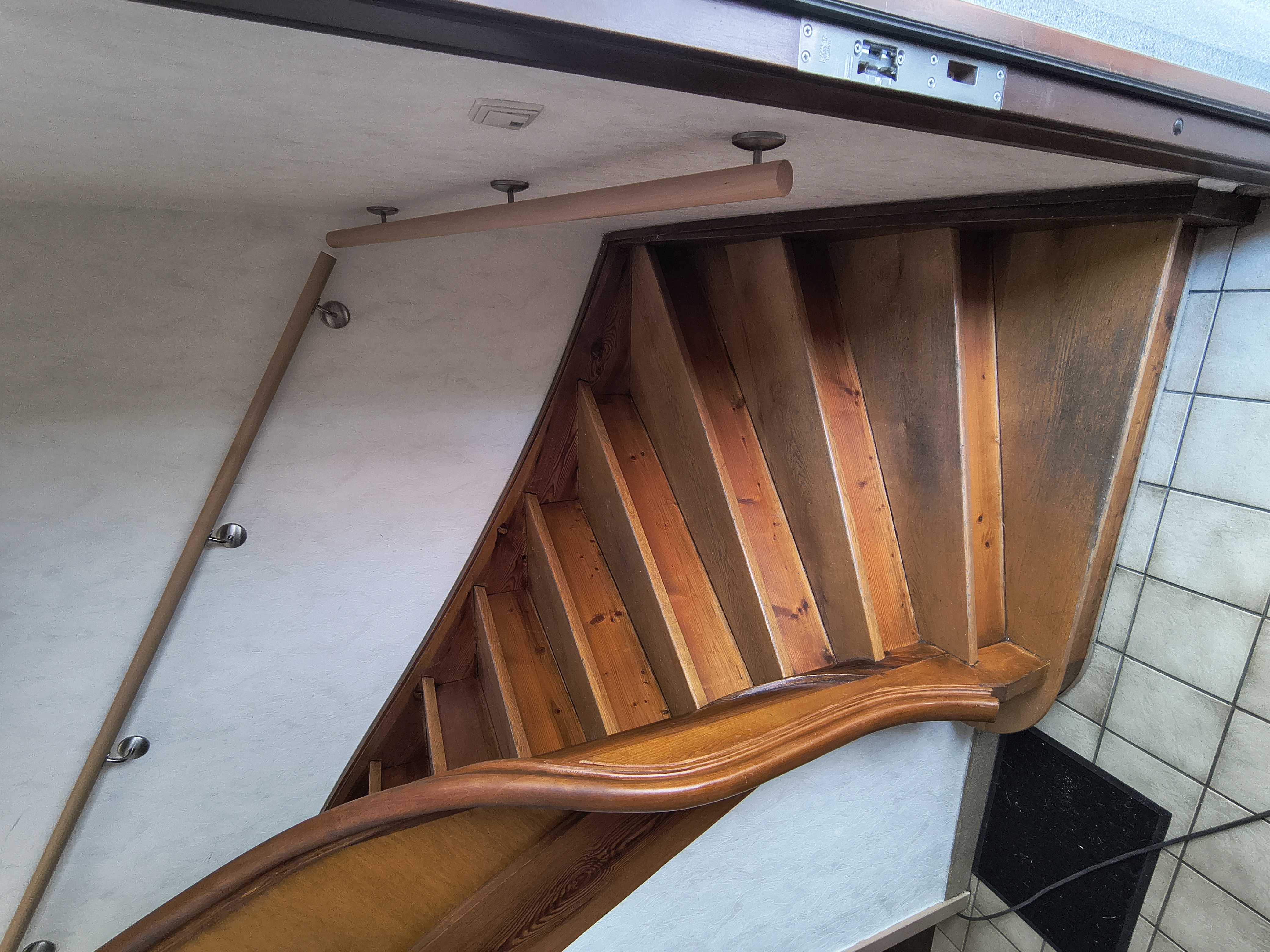 Maßgefertigter Handlauf aus Buche an einer bestehenden Holztreppe in einem Treppenhaus in Viernheim.