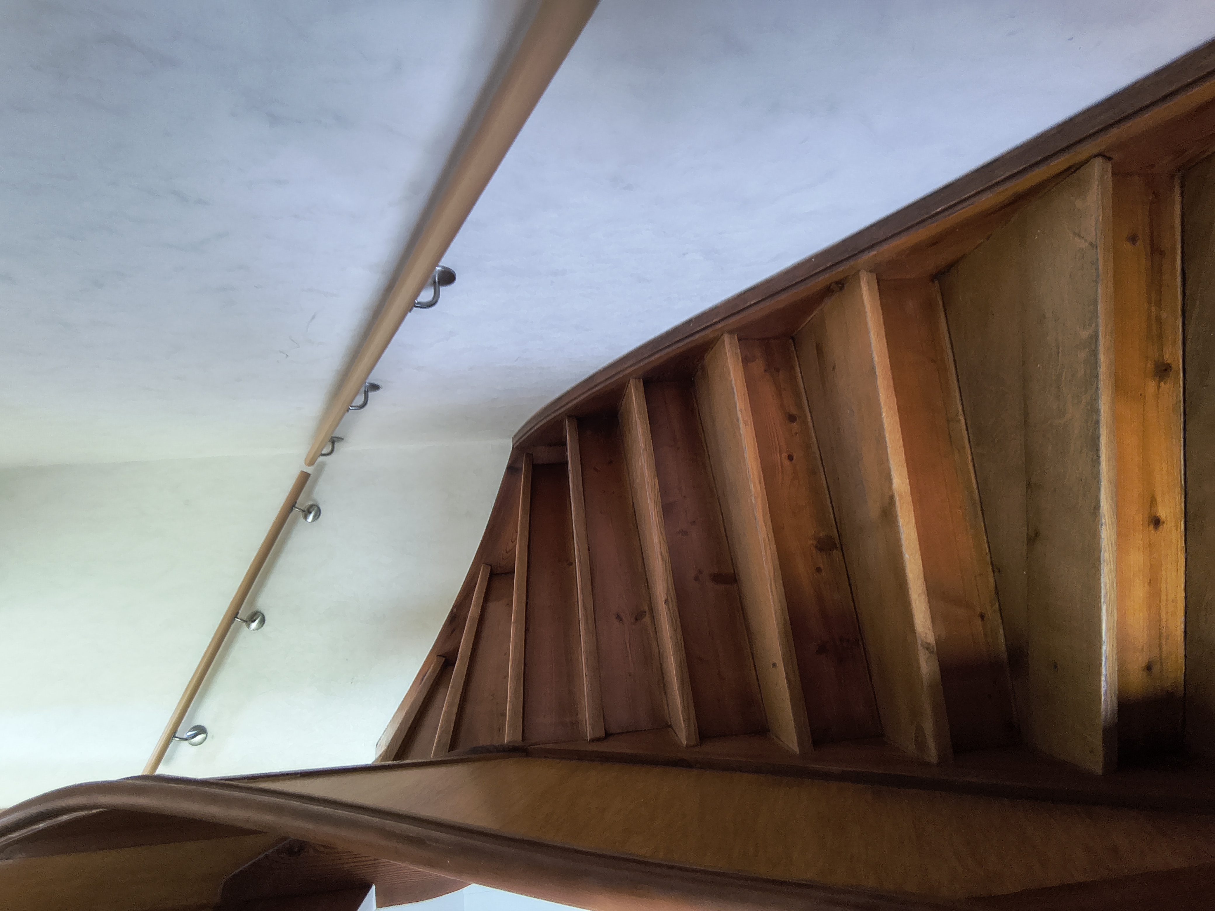Maßgefertigter Handlauf aus Buche mit Edelstahl-Wandhaltern entlang einer bestehenden Holztreppe in einem Wohnhaus in Viernheim.