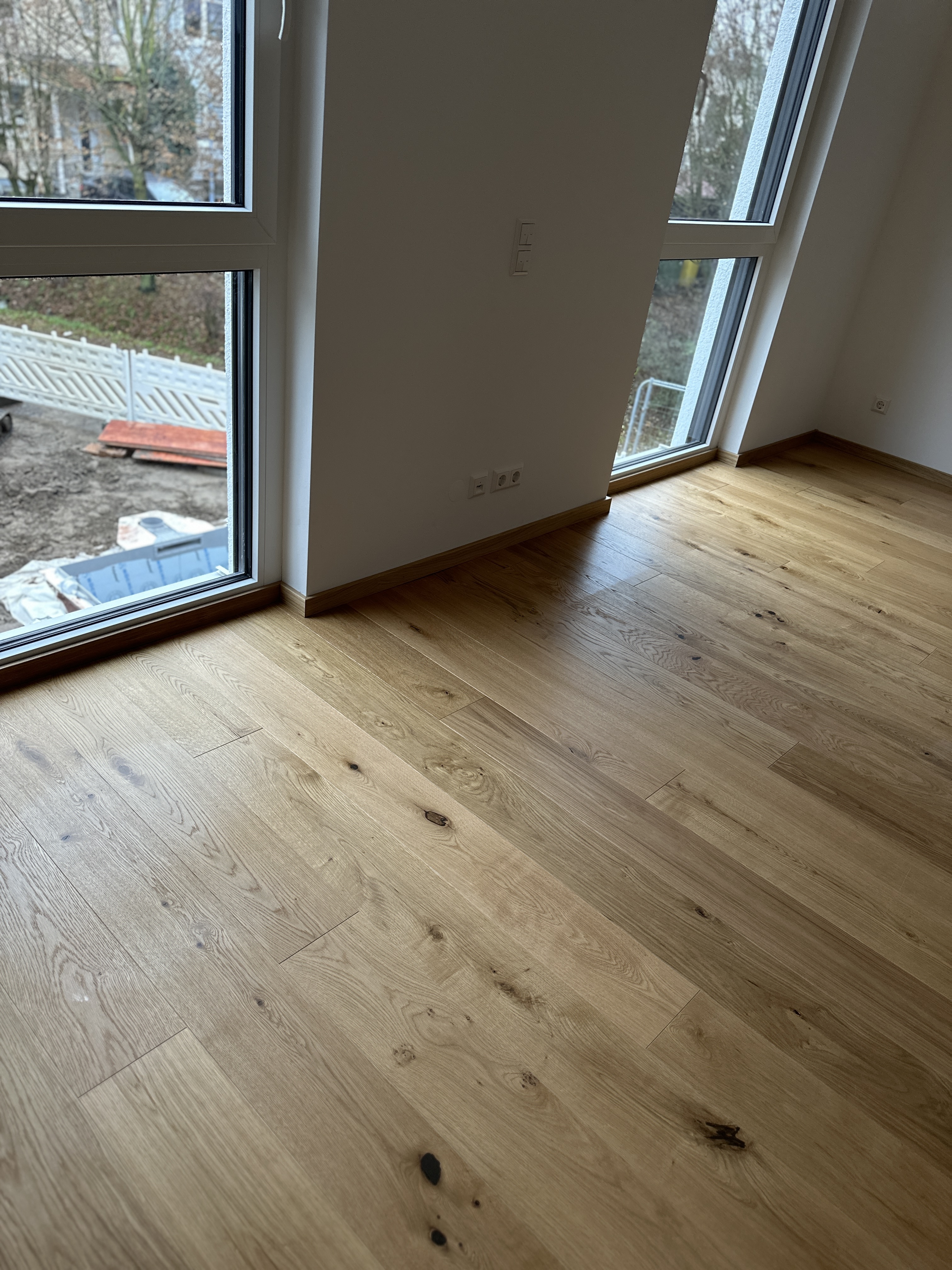 Eiche Landhausdielen mit natürlicher Maserung und passender Sockelleiste vor bodentiefen Fenstern im Neubau in Viernheim