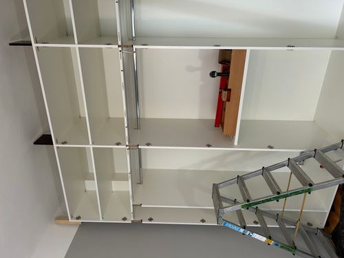 Montage des maßgefertigten Einbauschranks in Mannheim mit weißem Korpus, verstellbaren Fachböden und Kleiderstangen.