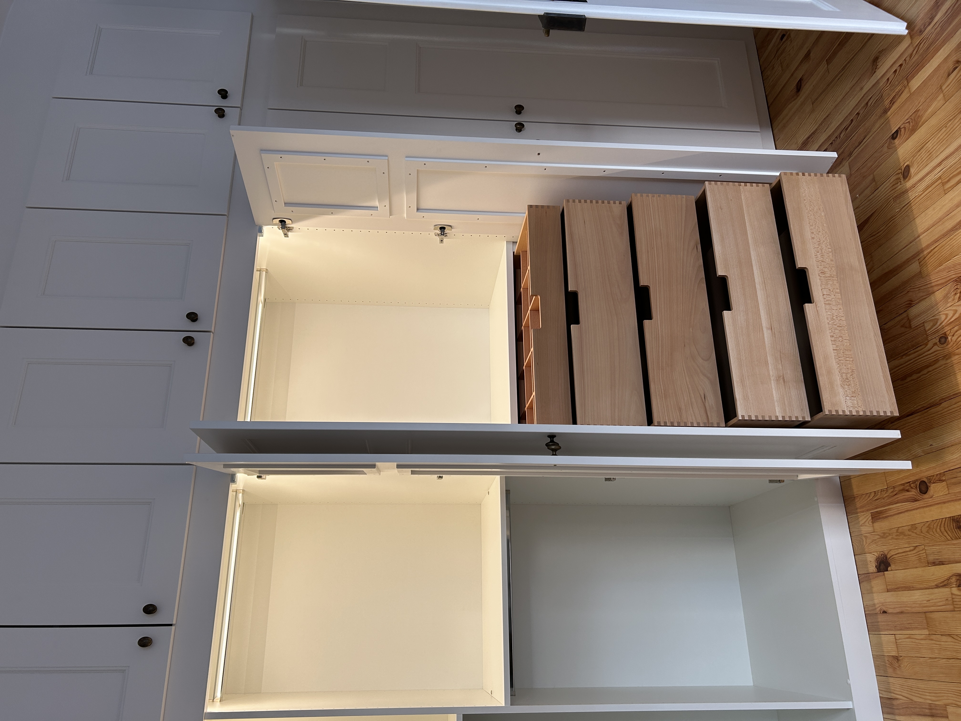 Maßgefertigter Einbauschrank in Mannheim mit geöffneten Rahmentüren, integrierter LED-Beleuchtung und fünf fingergezinkten Schubkästen aus Buche.