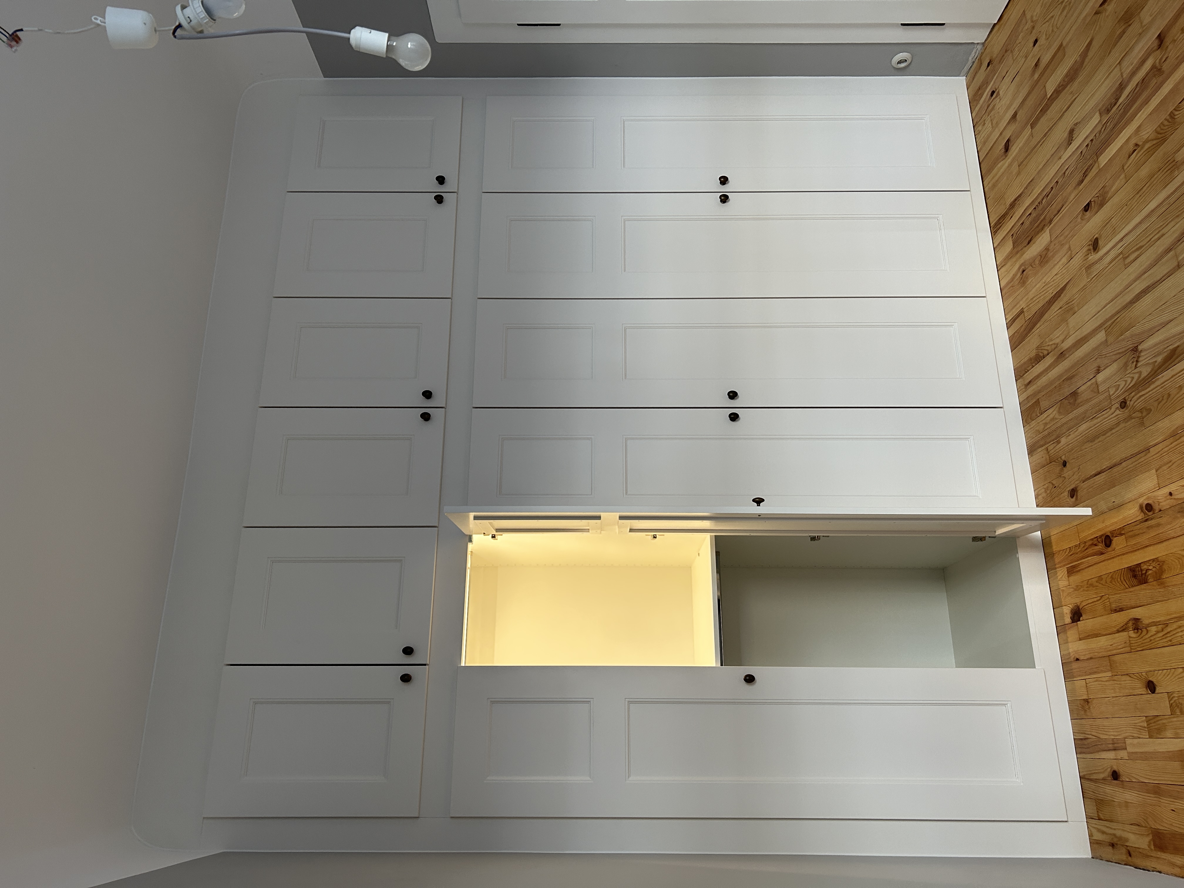 Maßgefertigter weißer Einbauschrank in Mannheim mit teilweise geöffneten Rahmentüren und integrierter LED-Innenbeleuchtung.