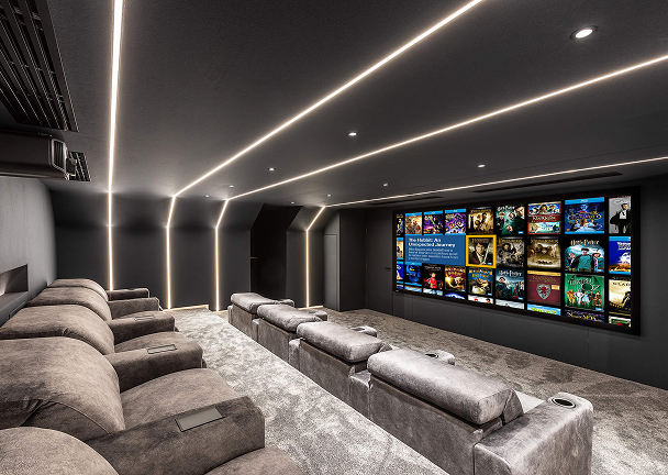 Modern home cinema featuring grey recliners and ambient ceiling lighting.