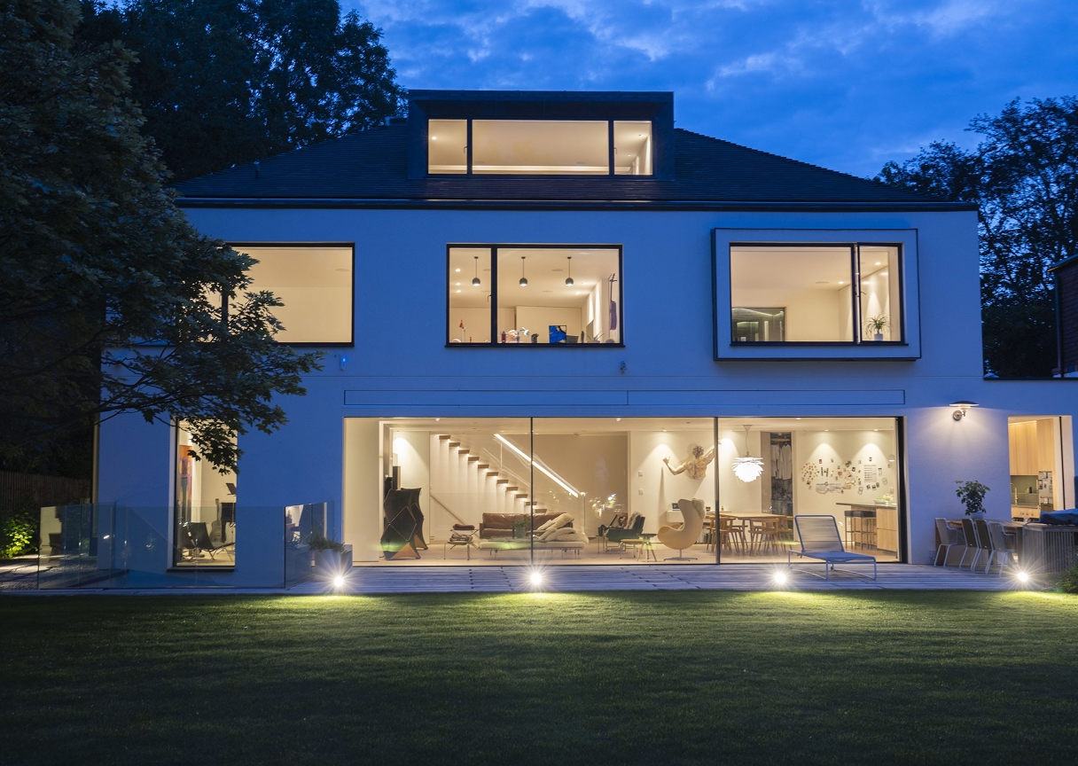 Contemporary home exterior at night showcasing balanced indoor and outdoor smart lighting powered by DALI control.