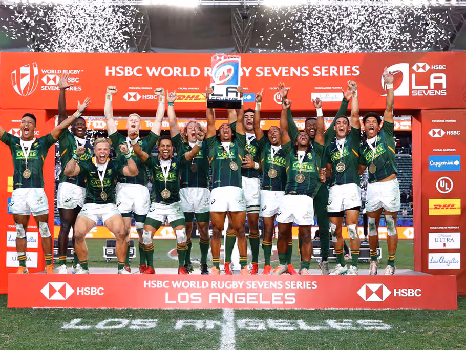 South African rugby team celebrating winning the HSBC World Rugby Sevens Series trophy in Los Angeles with confetti falling.