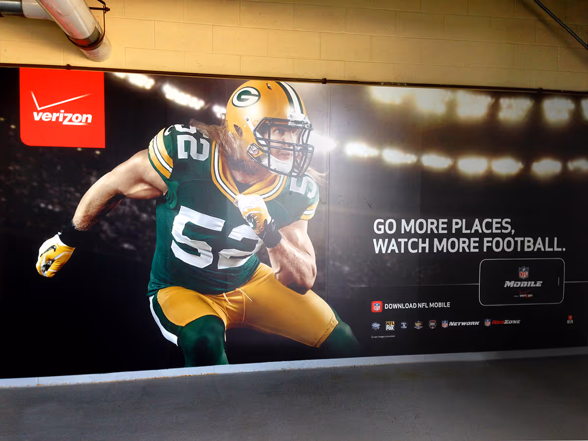 Verizon advertisement featuring a Green Bay Packers football player in action with the text 'Go more places, watch more football.'