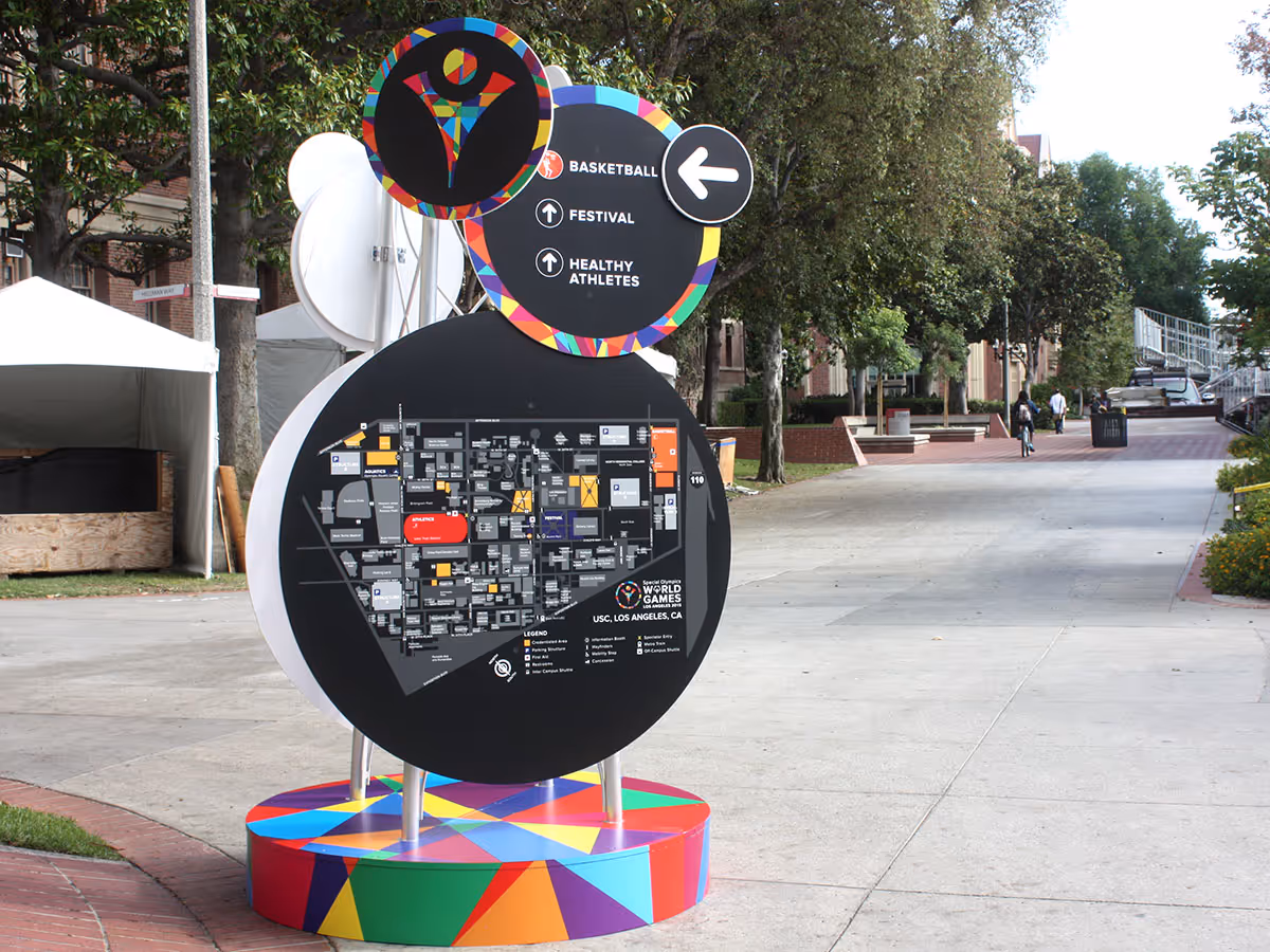 Colorful map and directional sign for Special Olympics World Games at USC campus with arrows pointing to basketball, festival, and healthy athletes areas.
