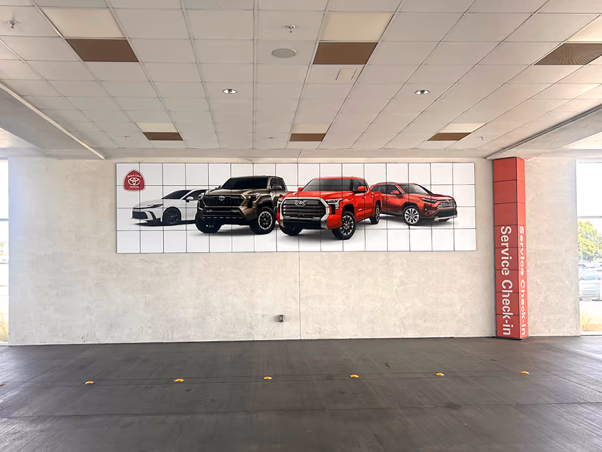 Toyota service check-in area with wall art showing a white sedan, a black truck, a red truck, and a red SUV.