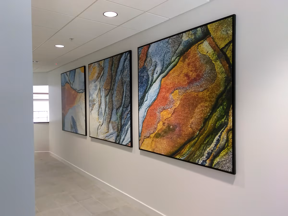 Modern hallway with Silicone edged Graphic frame with three colorful abstract stone-patterned fabric prints on a white wall.