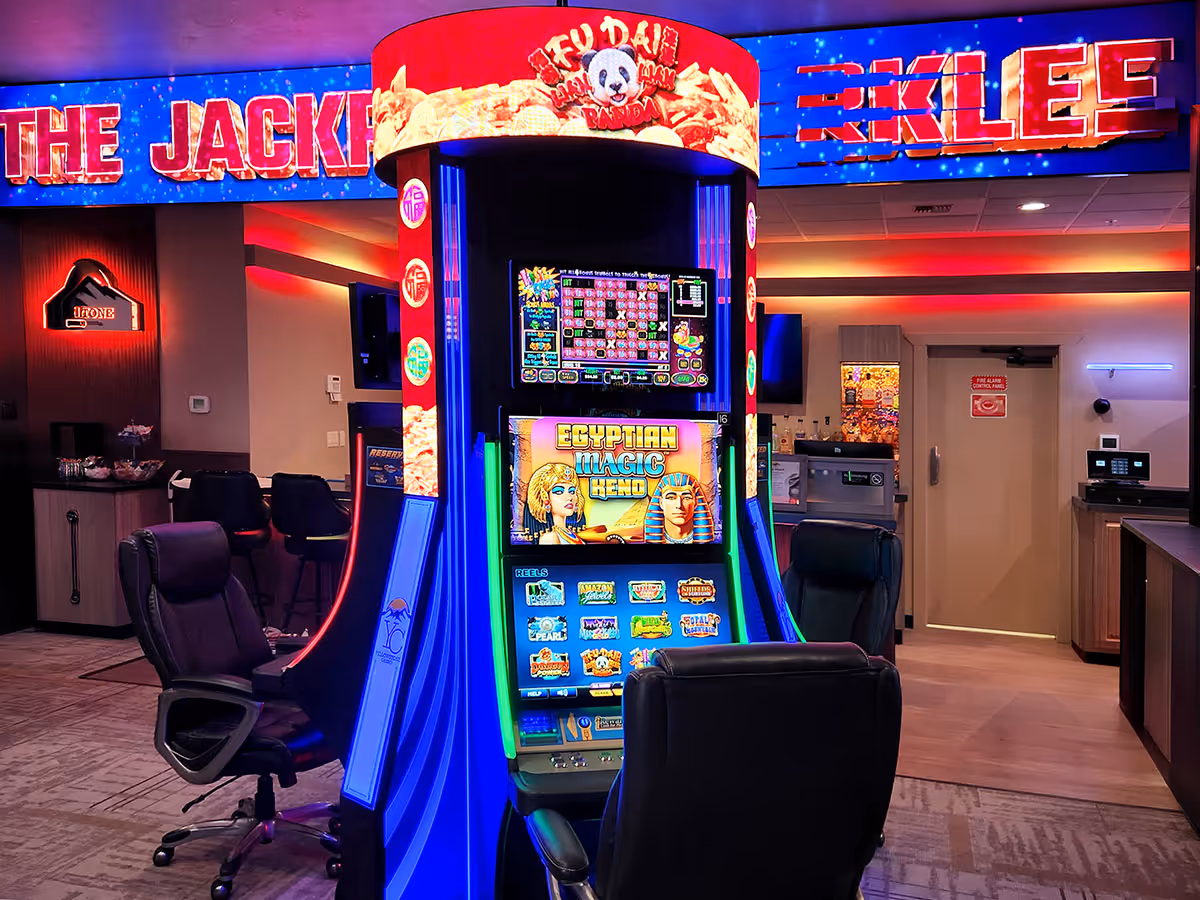 Casino slot machine with Egyptian Magic theme, surrounded by black chairs and illuminated by colorful neon lights.