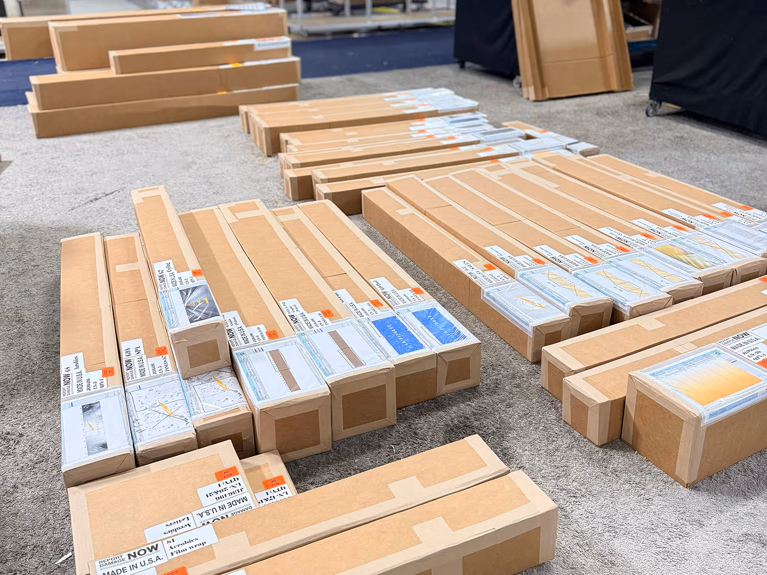 Multiple rectangular cardboard shipping boxes with labels and taped edges neatly arranged on a carpeted floor.