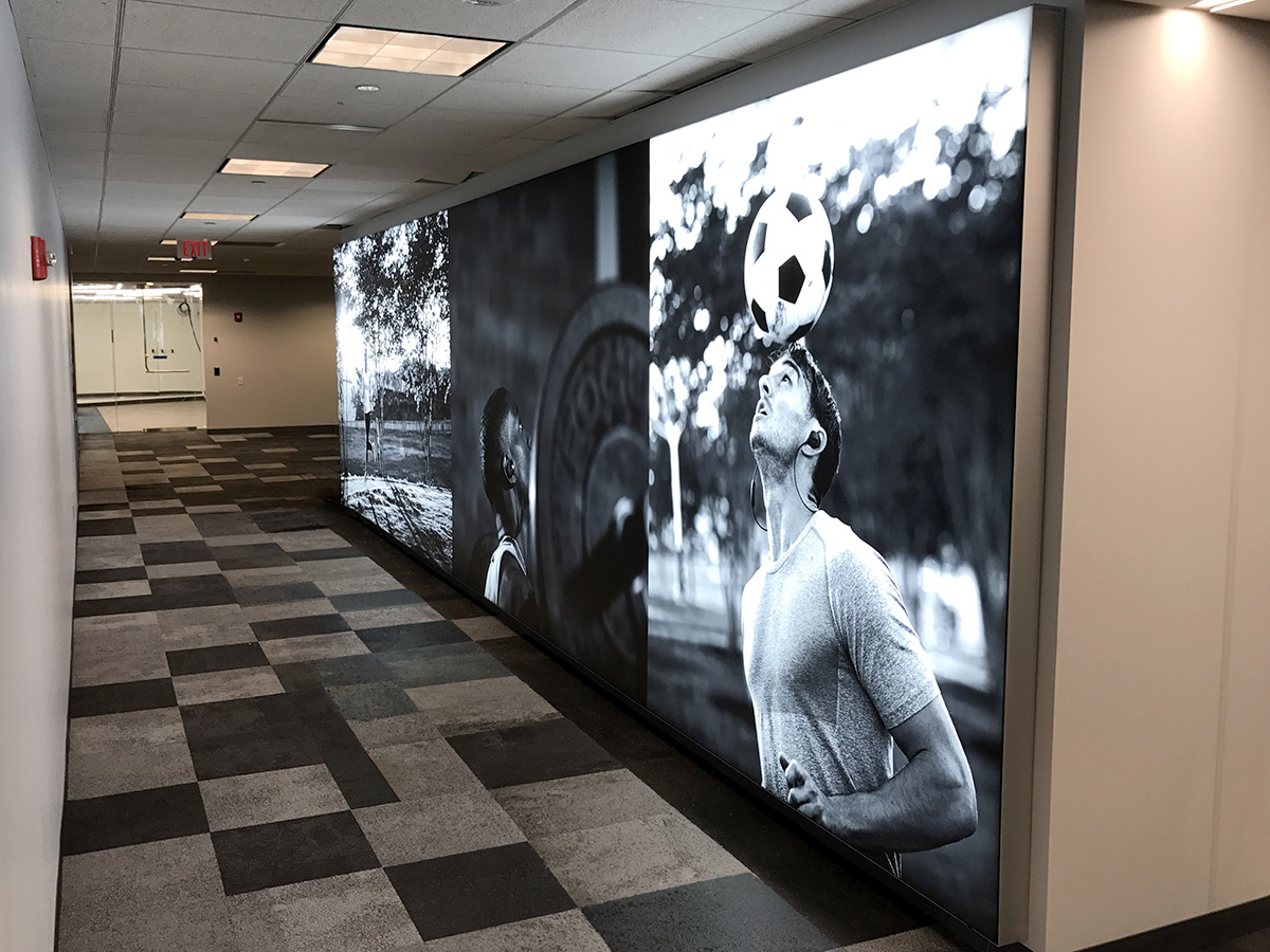Leather work boot displayed on a black pedestal with a glowing white top in an industrial setting.