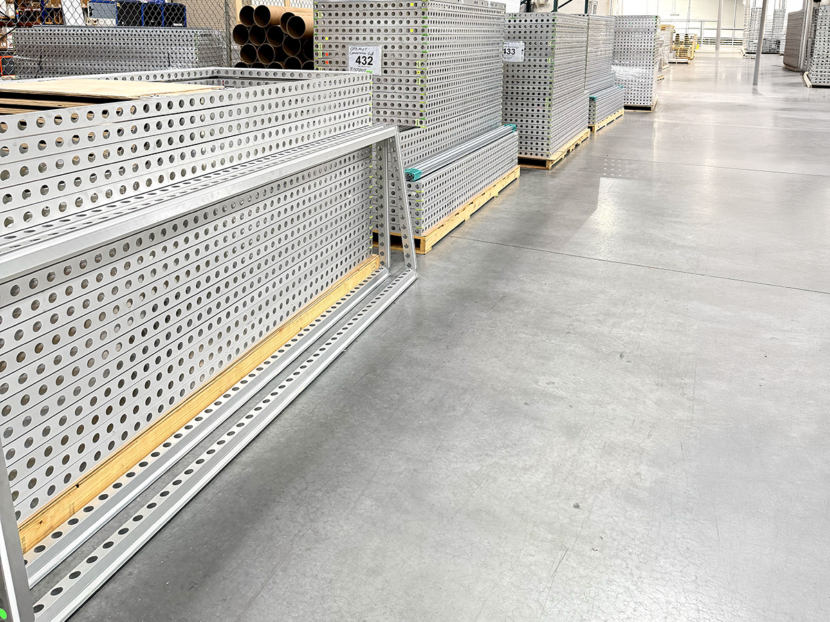 Stacks of Bematrix frames with circular holes neatly arranged on pallets in a warehouse aisle.