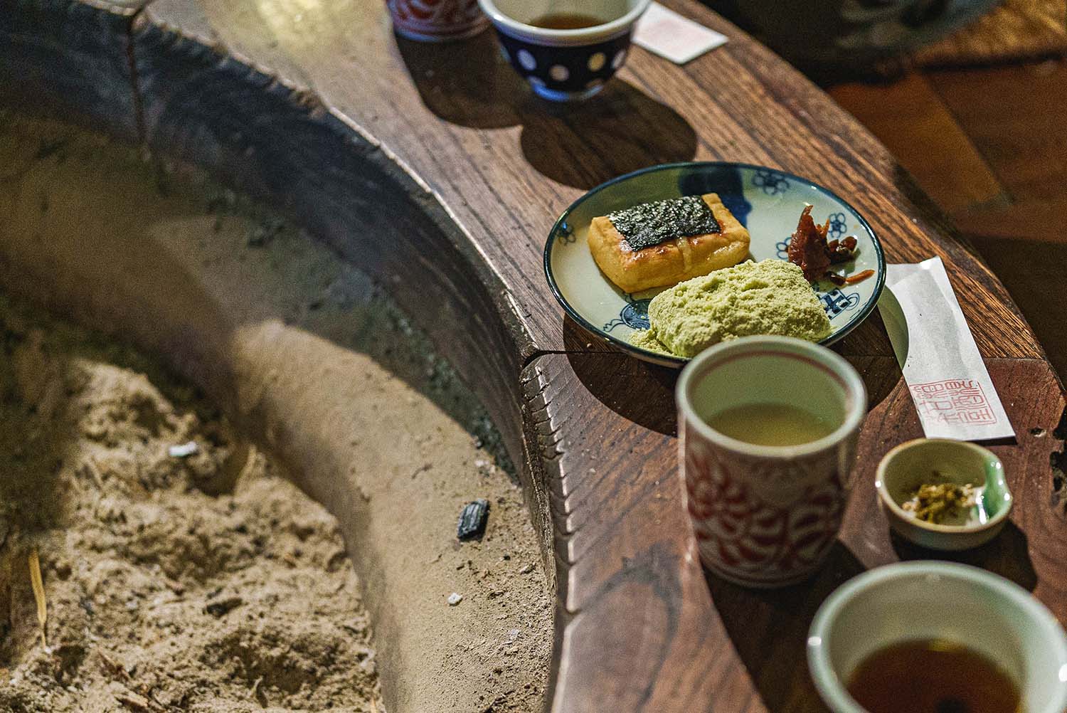 A plate of toasted chikara-mochi with kinako served alongside cups of warm amazake
