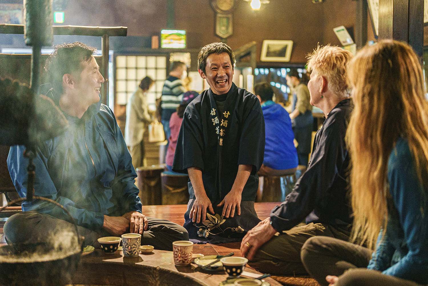 The owner of Amasake Chaya in a happi coat sharing conversation with guests over amazake