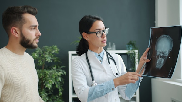 Patient and doctor are looking at x-ray images in clinic office talking discussing disease. People, healthcare and contemporary hospitals concept.