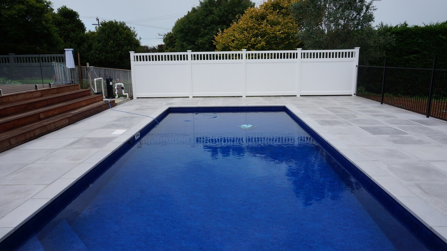 A swimming pool with concrete copying and pavers by The Paving Lab Company.