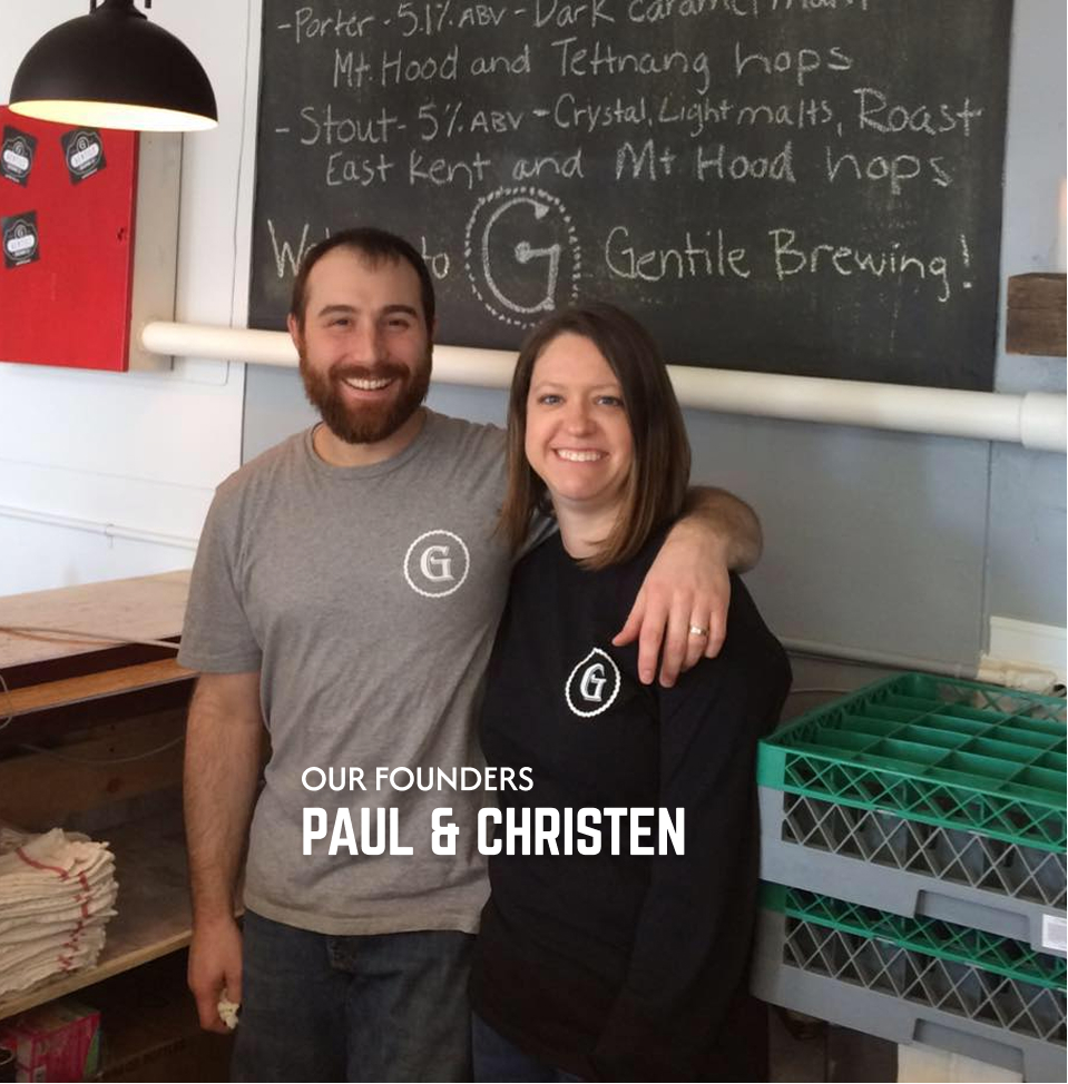 Smiling man and woman wearing Gentile Brewing shirts standing inside a brewery with chalkboard behind them.