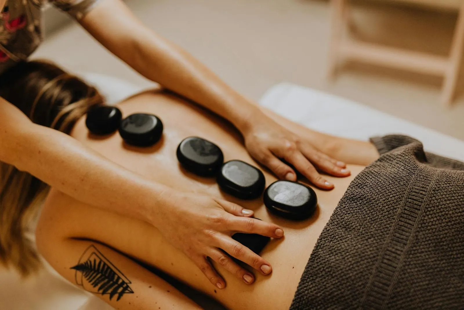 Person receiving a hot stone massage on their back