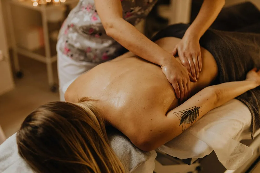 Therapist massaging client’s back with oil