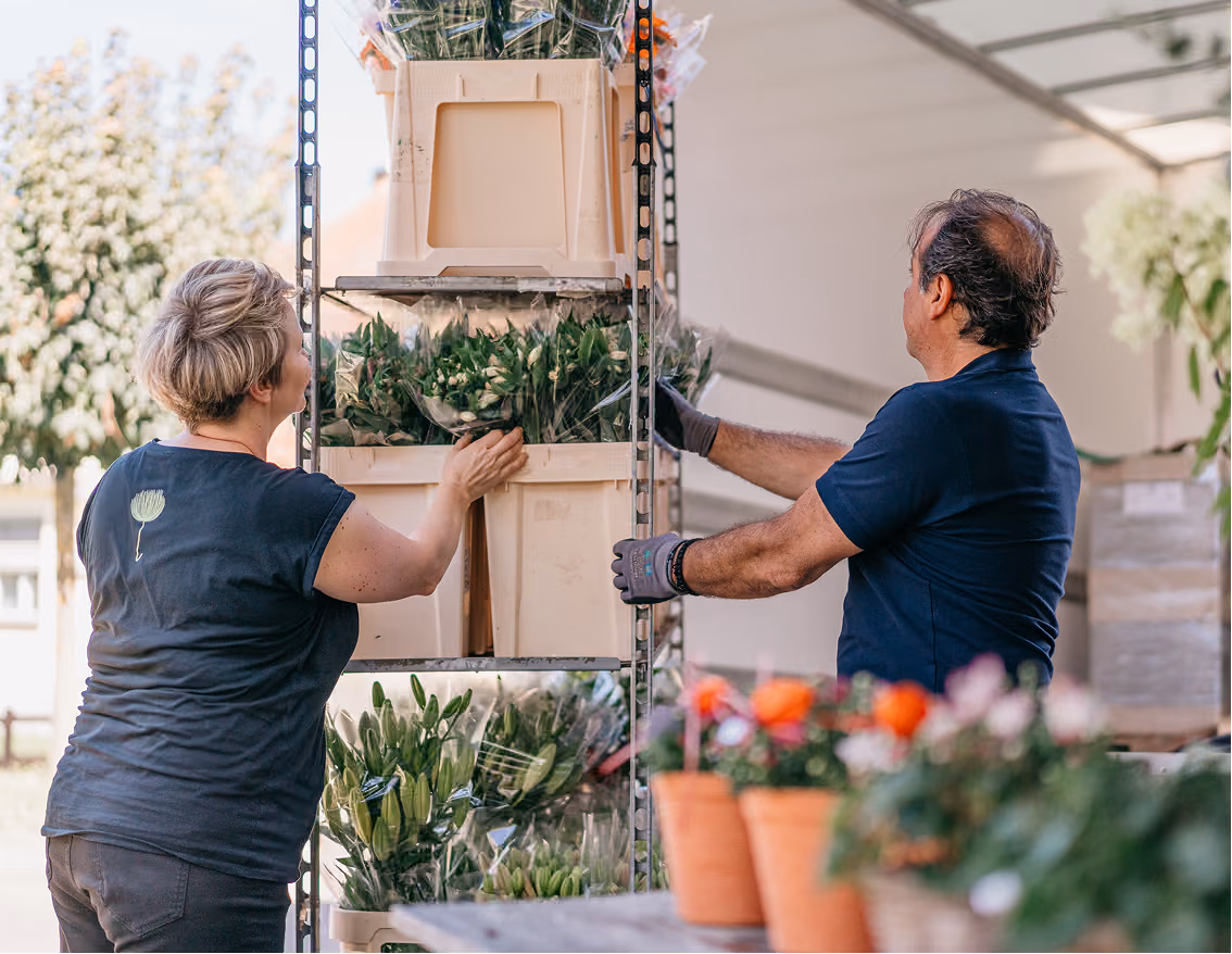 Roland Koch Transporte Schweiz: Zwei Mitarbeiter ordnen Blumen im Lagerregal