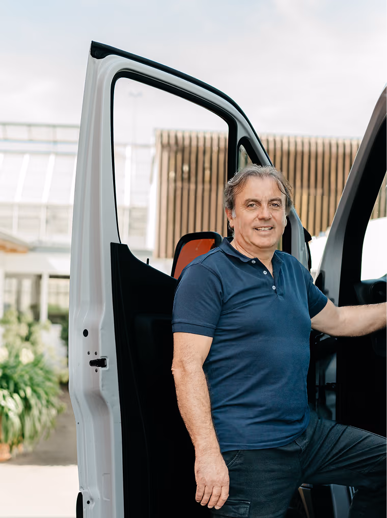 Roland Koch von Transporte Schweiz steht lächelnd neben seinem Lieferwagen