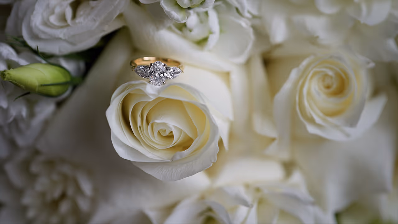 Diamond engagement ring resting on white roses, captured in soft natural light by Creo Bella.