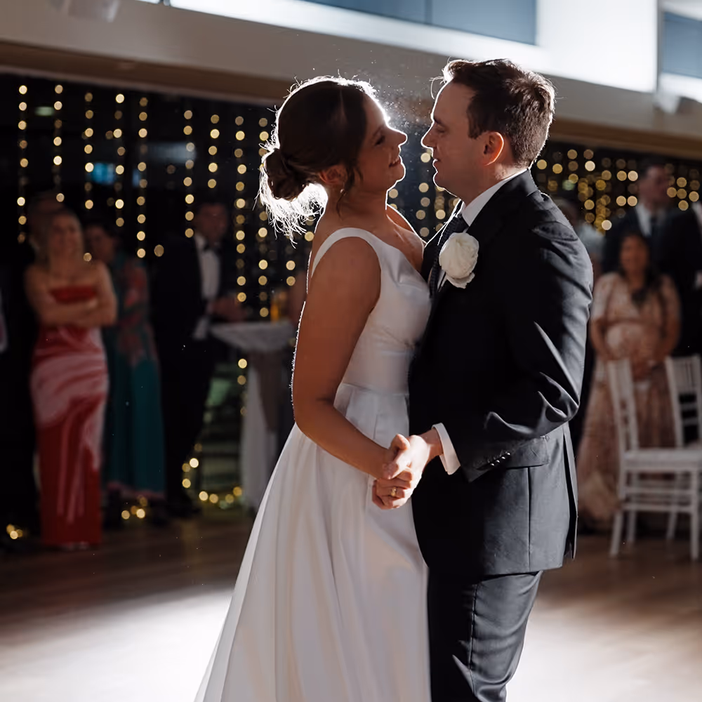 Bride and groom sharing their first dance under soft lights at their wedding reception, captured in cinematic style by Creo Bella.