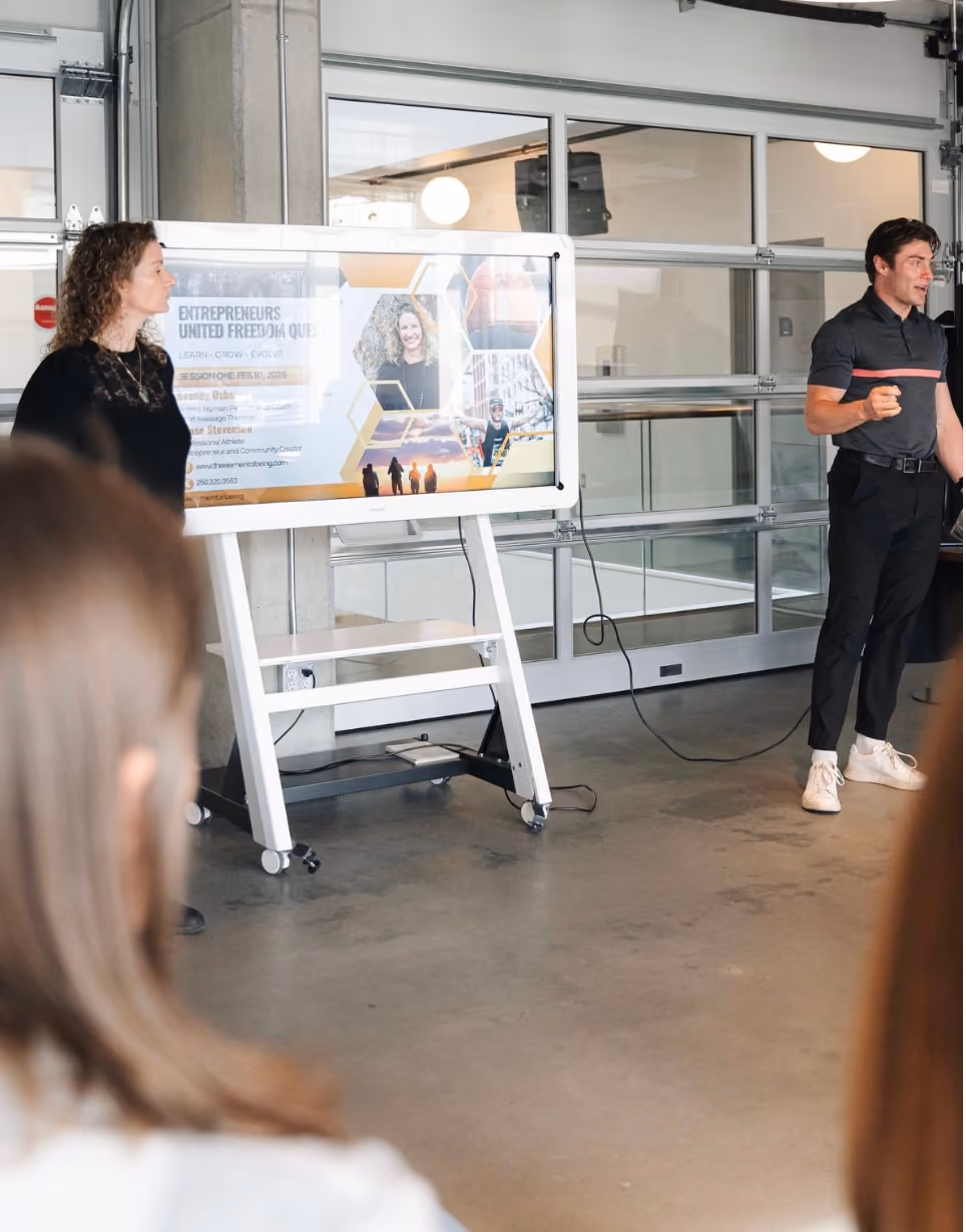 Man and woman giving a presentation with slides in a modern room with an audience.