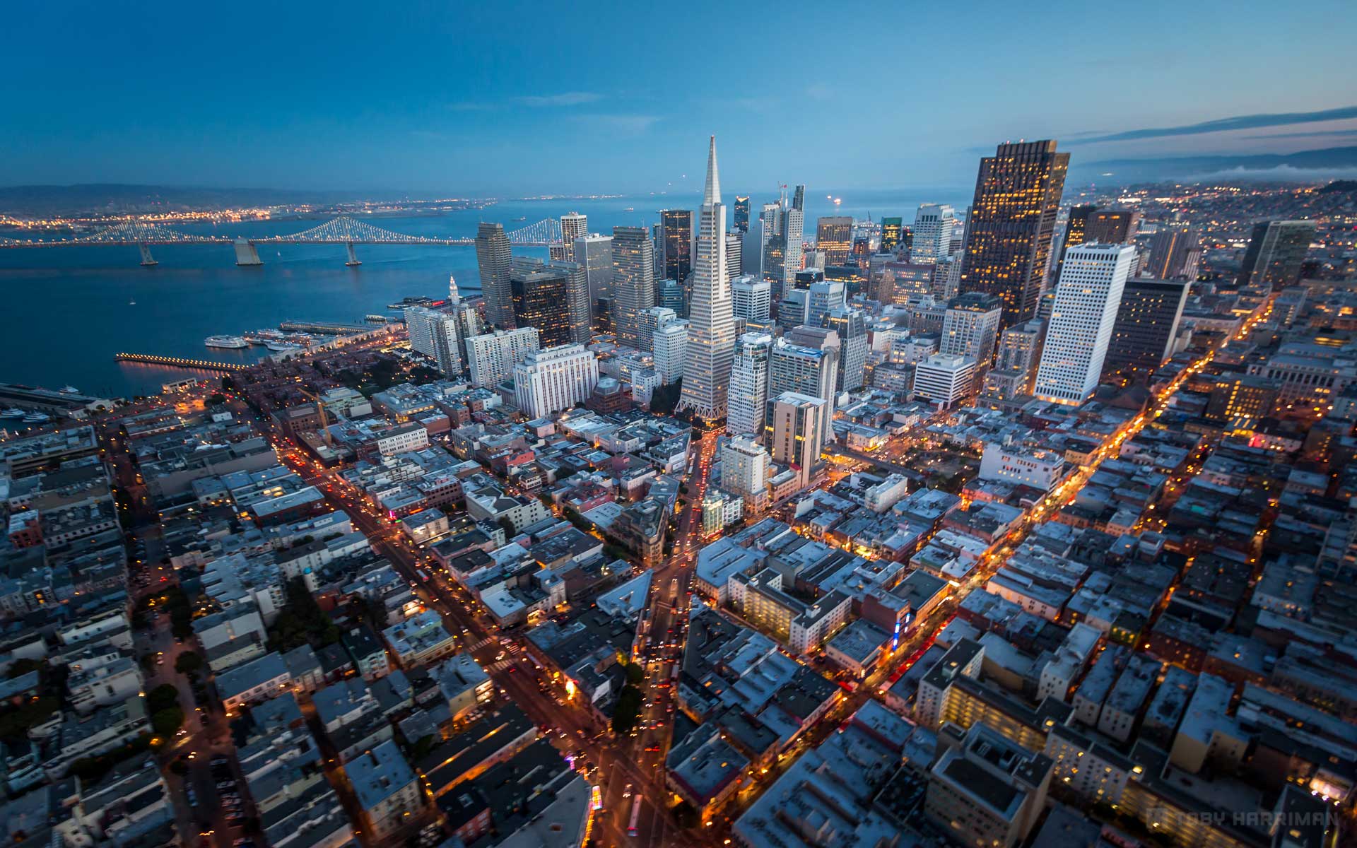 Aerial view of San Francisco at dusk, featuring the Transamerica Pyramid and Bay Bridge.
