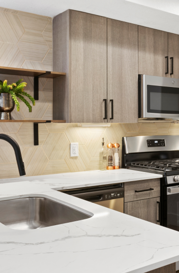 Modern kitchen with wood cabinets, hexagonal backsplash, and marble-style countertops.