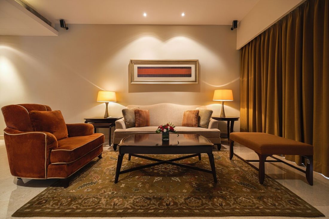 A cozy living room with warm lighting, elegant furniture, and a patterned rug.