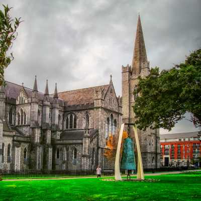 St. Patrick's Cathedral in Dublin, Ireland, with a modern bell sculpture in the foreground.